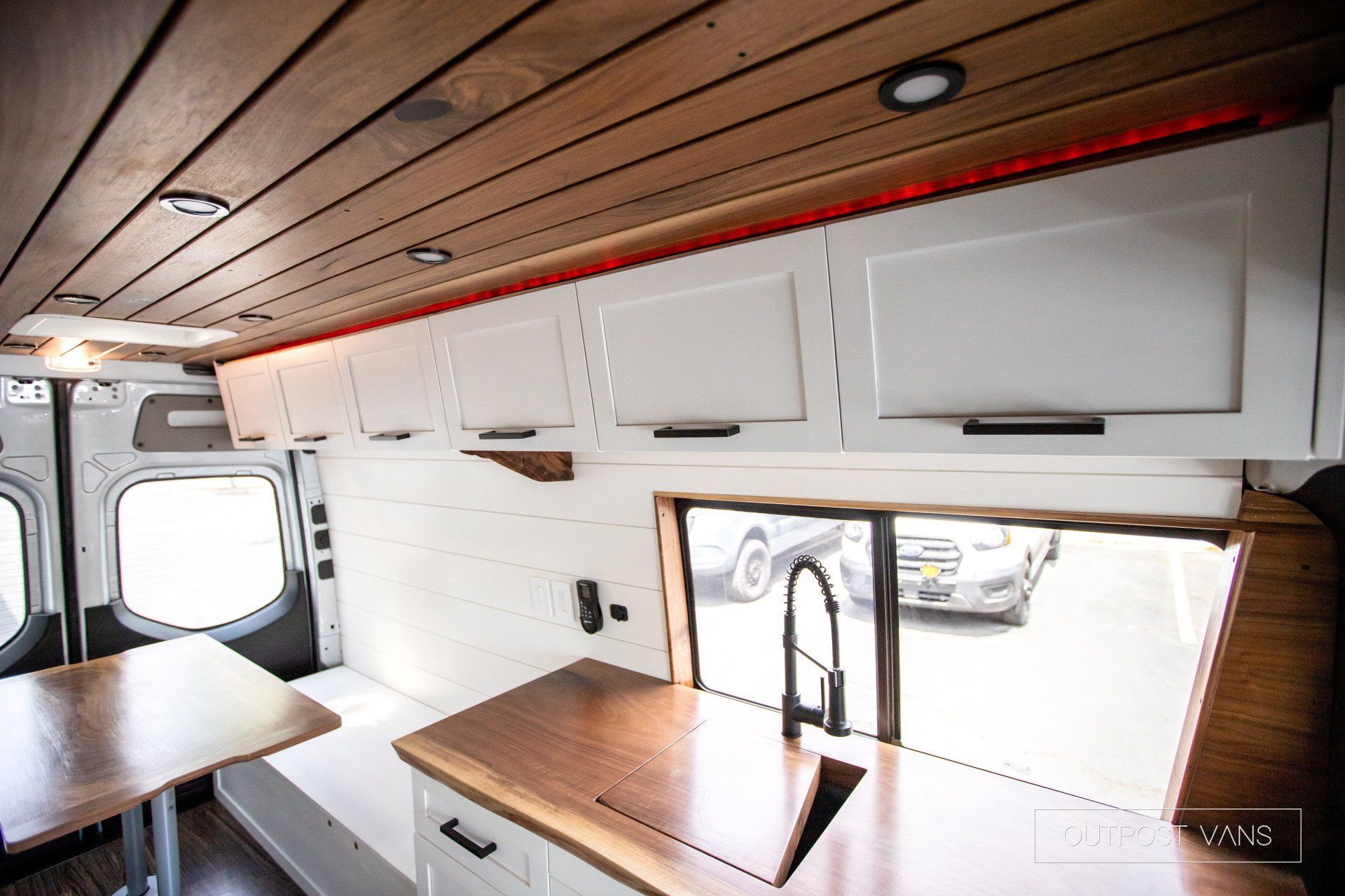 A kitchen in a van with a sink and a table.