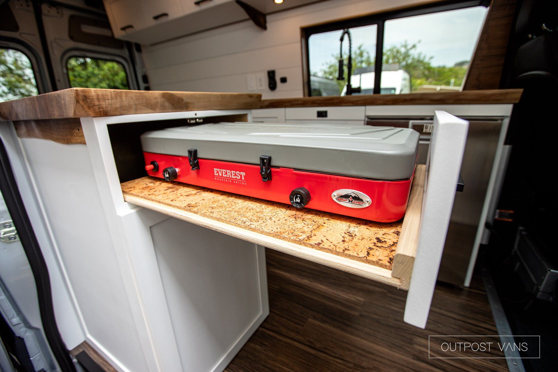 A portable stove is sitting on top of a drawer in a kitchen.
