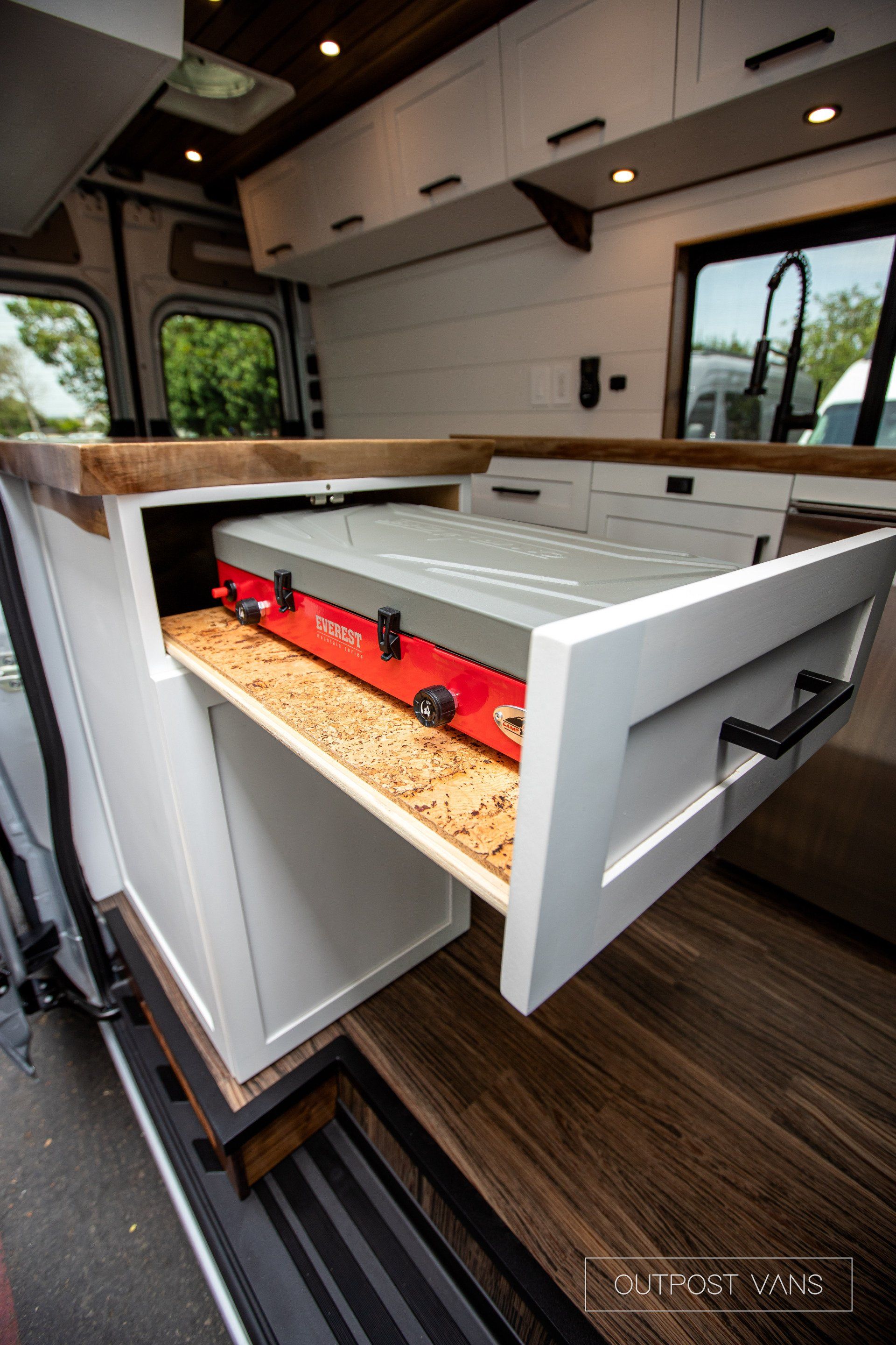A kitchen in a van with a stove in a drawer.