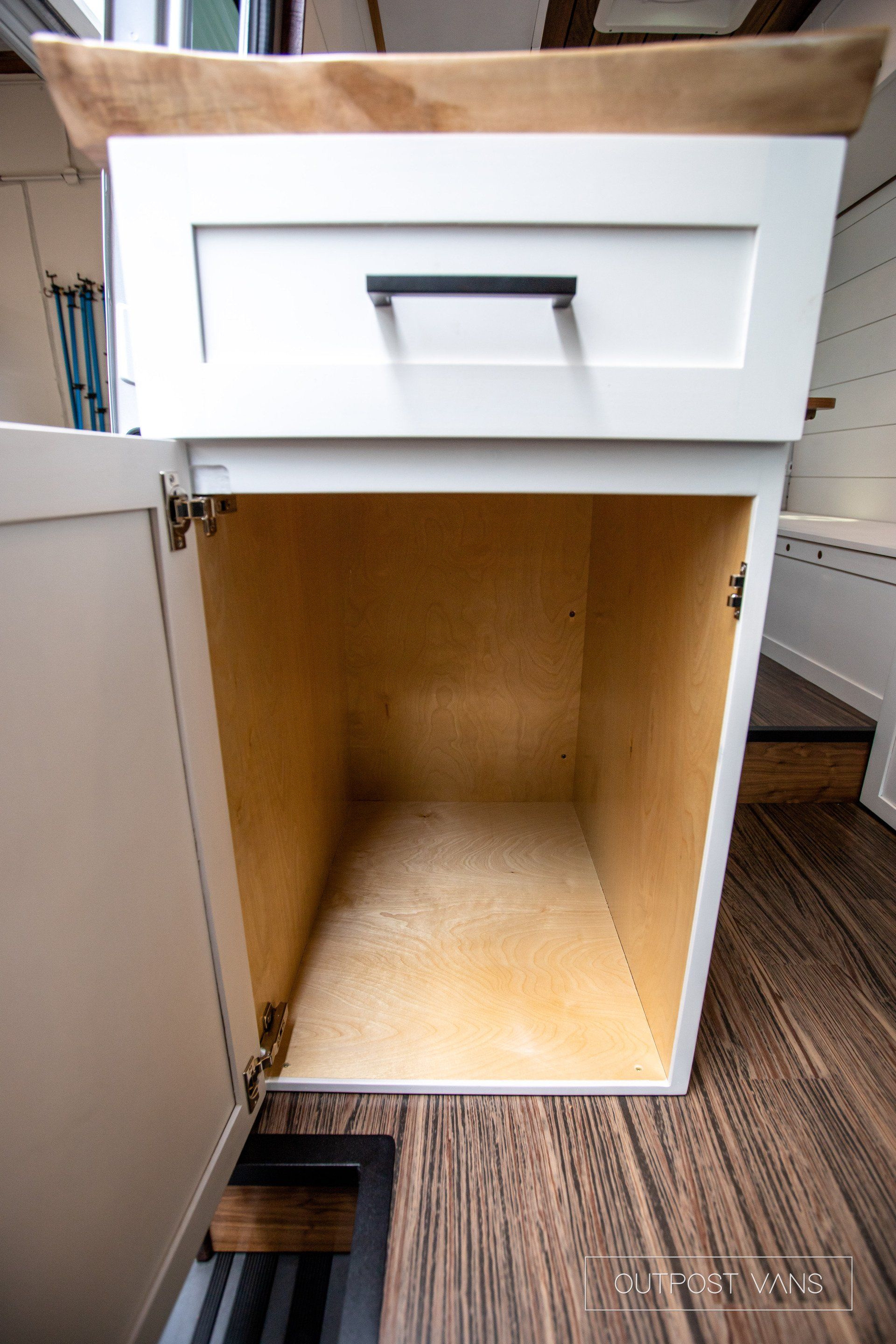 A white cabinet with the door open and a wooden counter top.