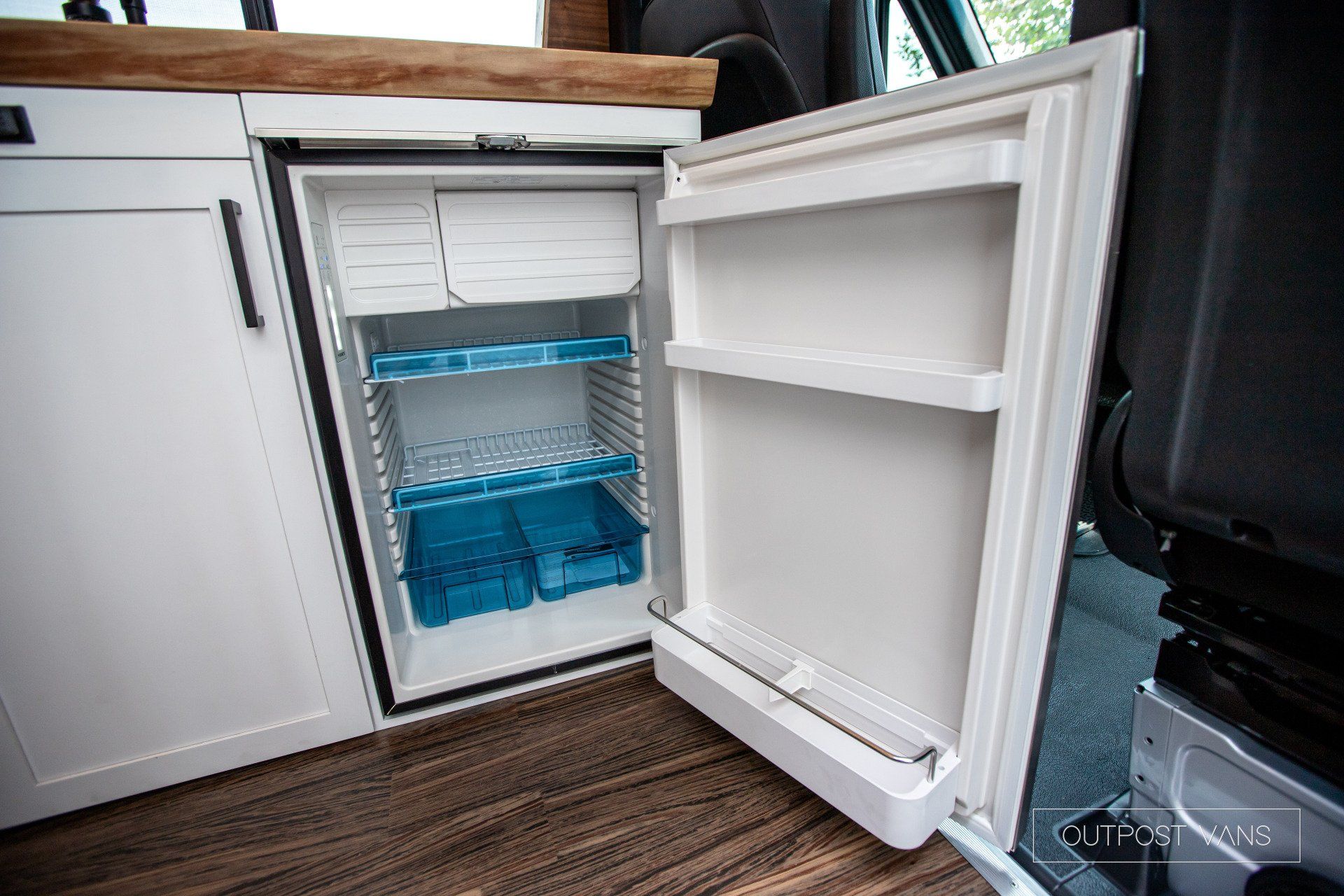A small refrigerator with the door open in a van.
