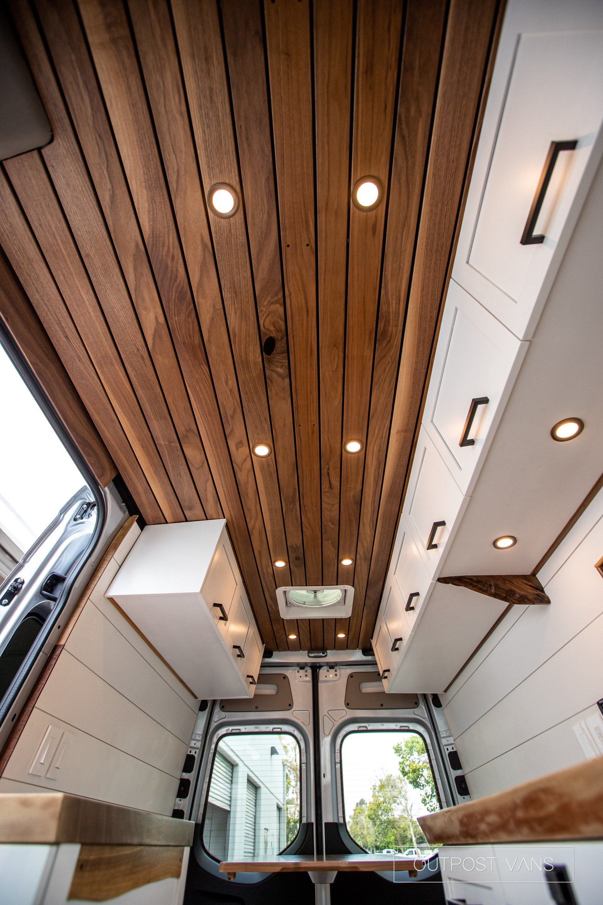 The inside of a van with a wooden ceiling and cabinets.