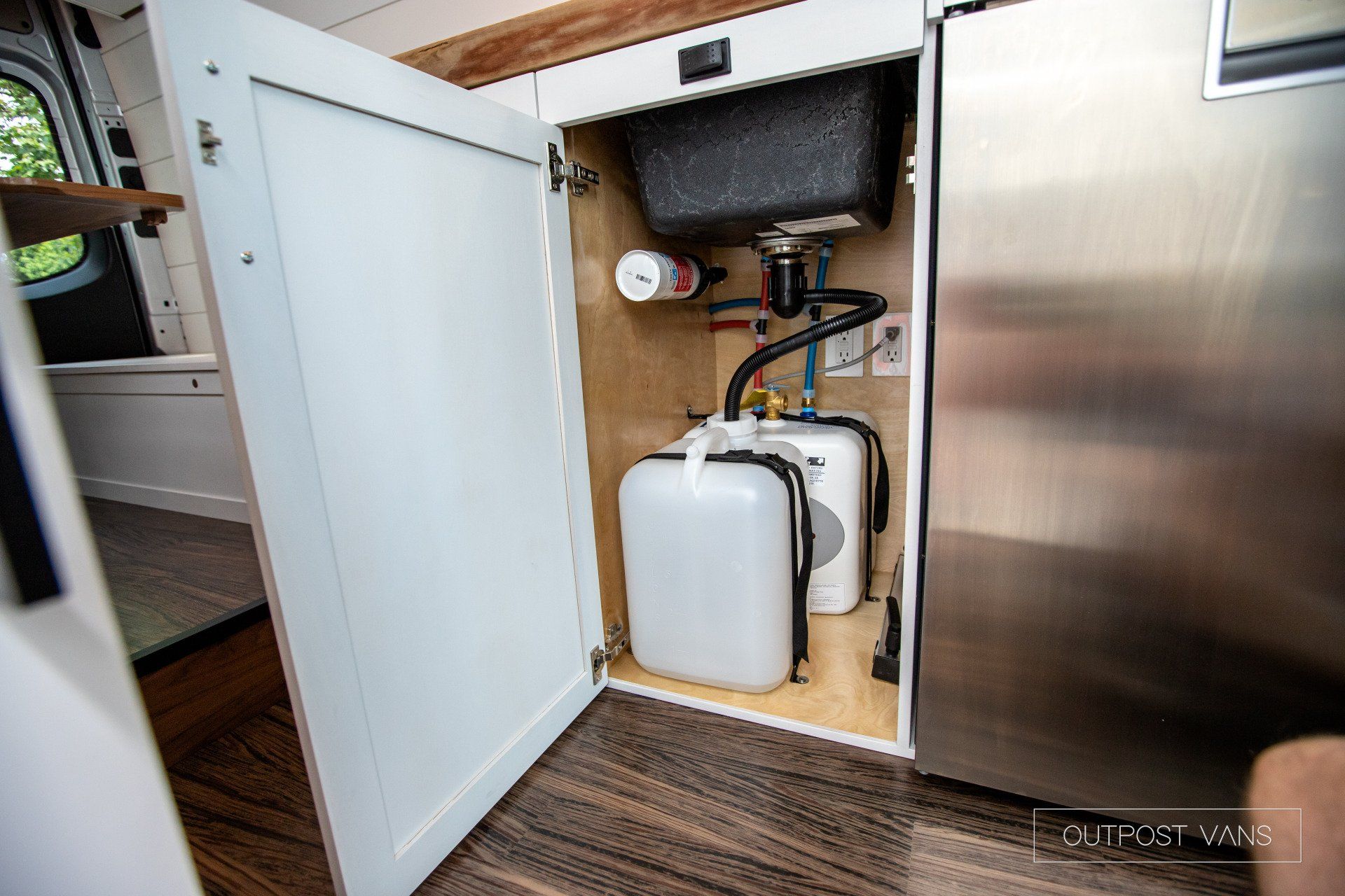 A kitchen cabinet with a sink and two bottles underneath it.