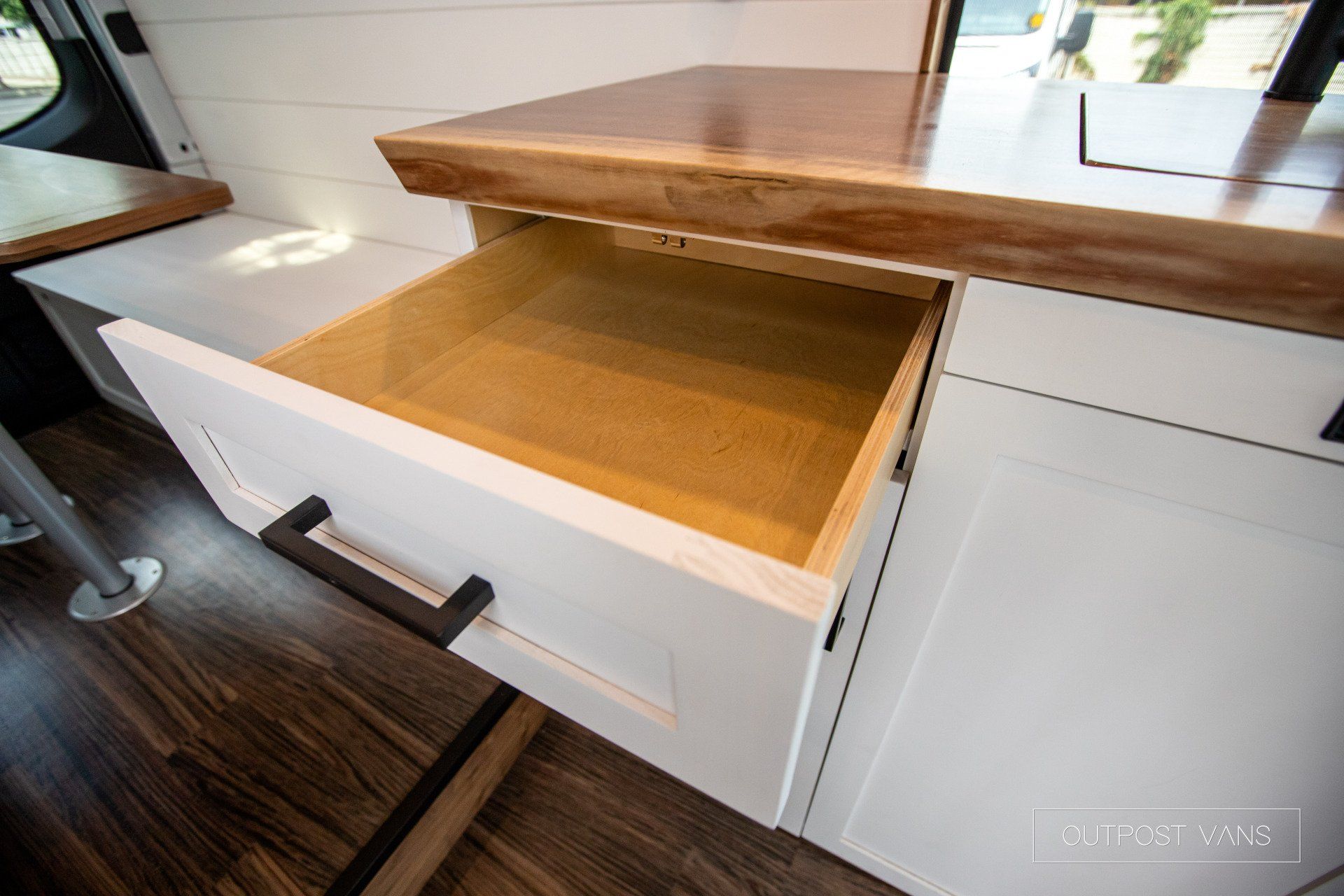 An open drawer in a kitchen with a wooden counter top.