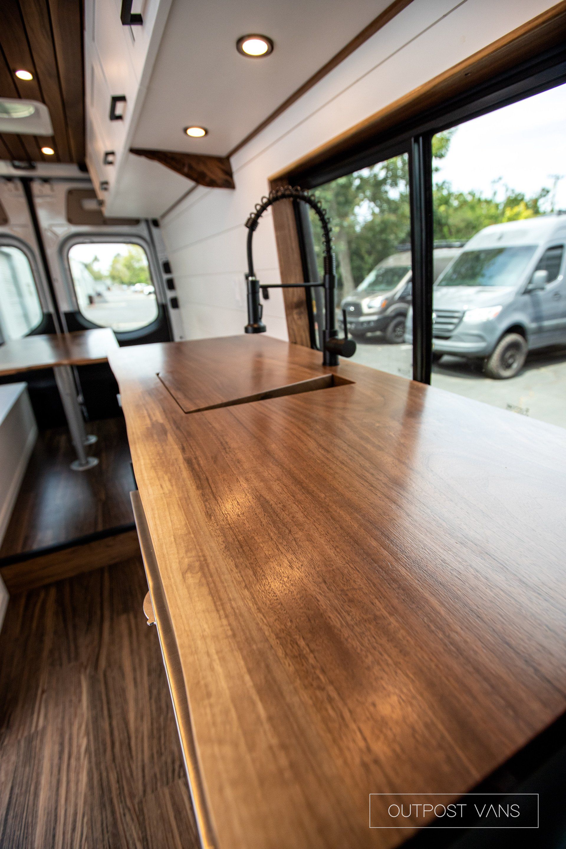 A kitchen in a van with a wooden counter top and a sink.