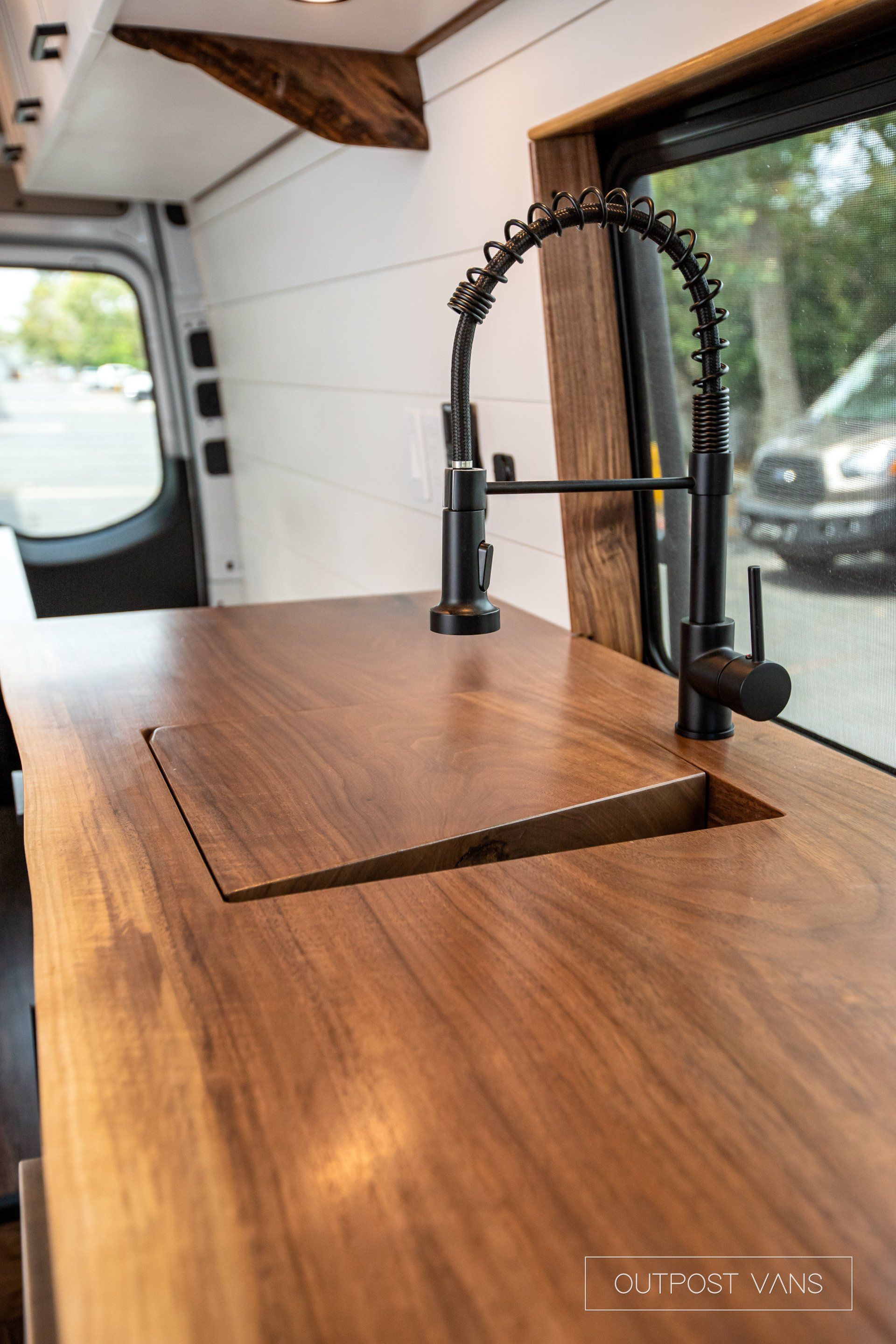A kitchen sink with a wooden counter top and a black faucet.