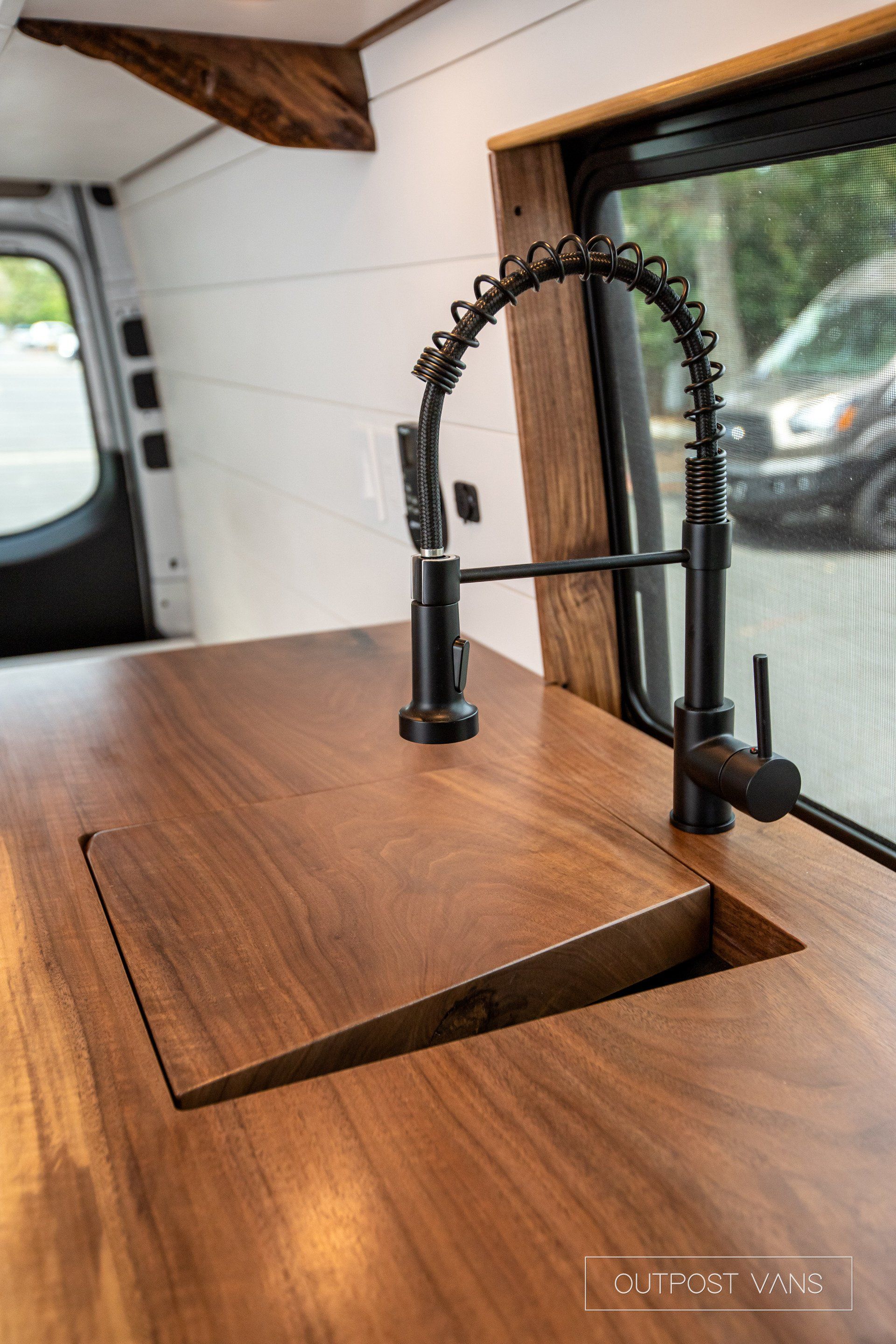 A sink with a faucet on a wooden counter in a van.