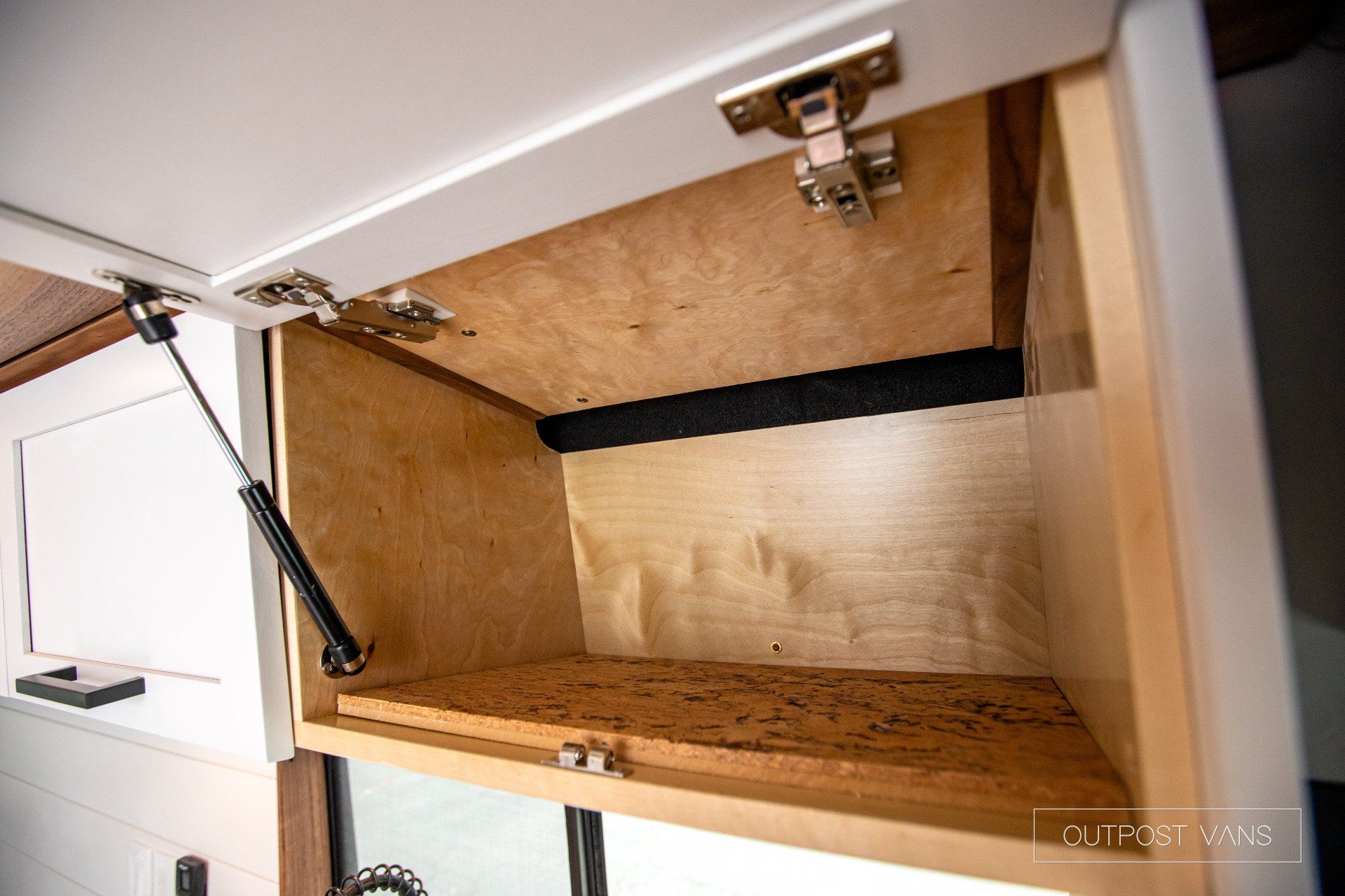 The inside of a cabinet with the door open and a gas spring.