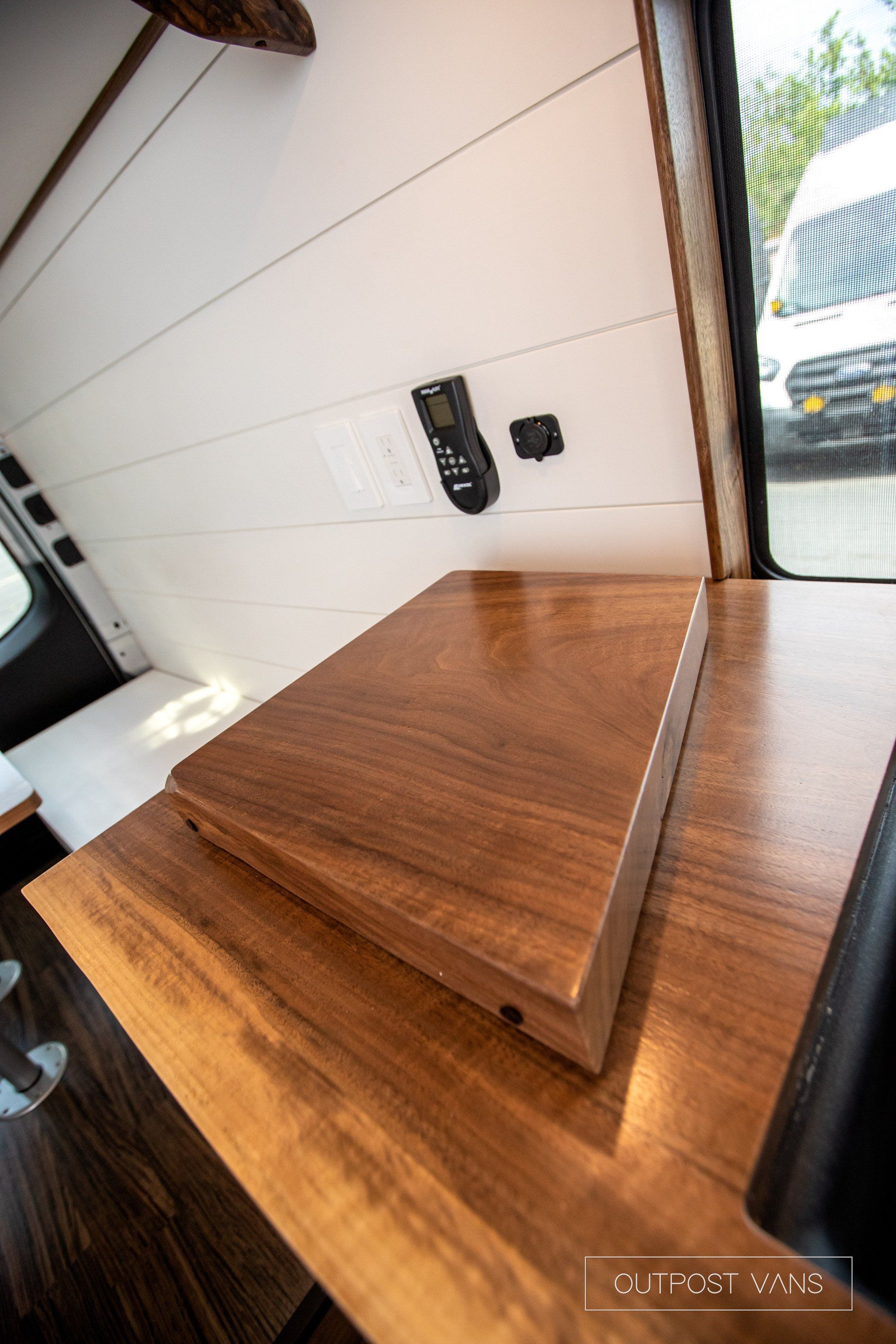 A wooden table with a remote control on it in a van.