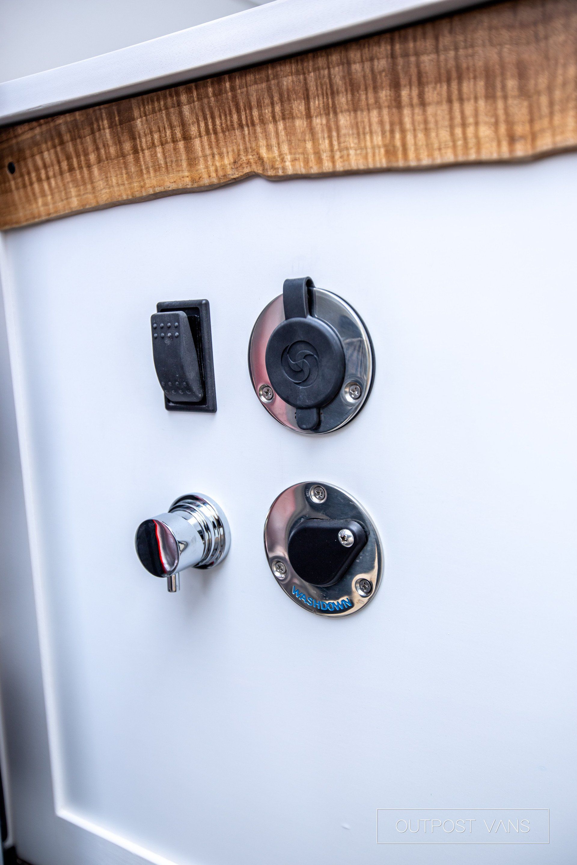 A close up of a white cabinet with electrical outlets and a switch.