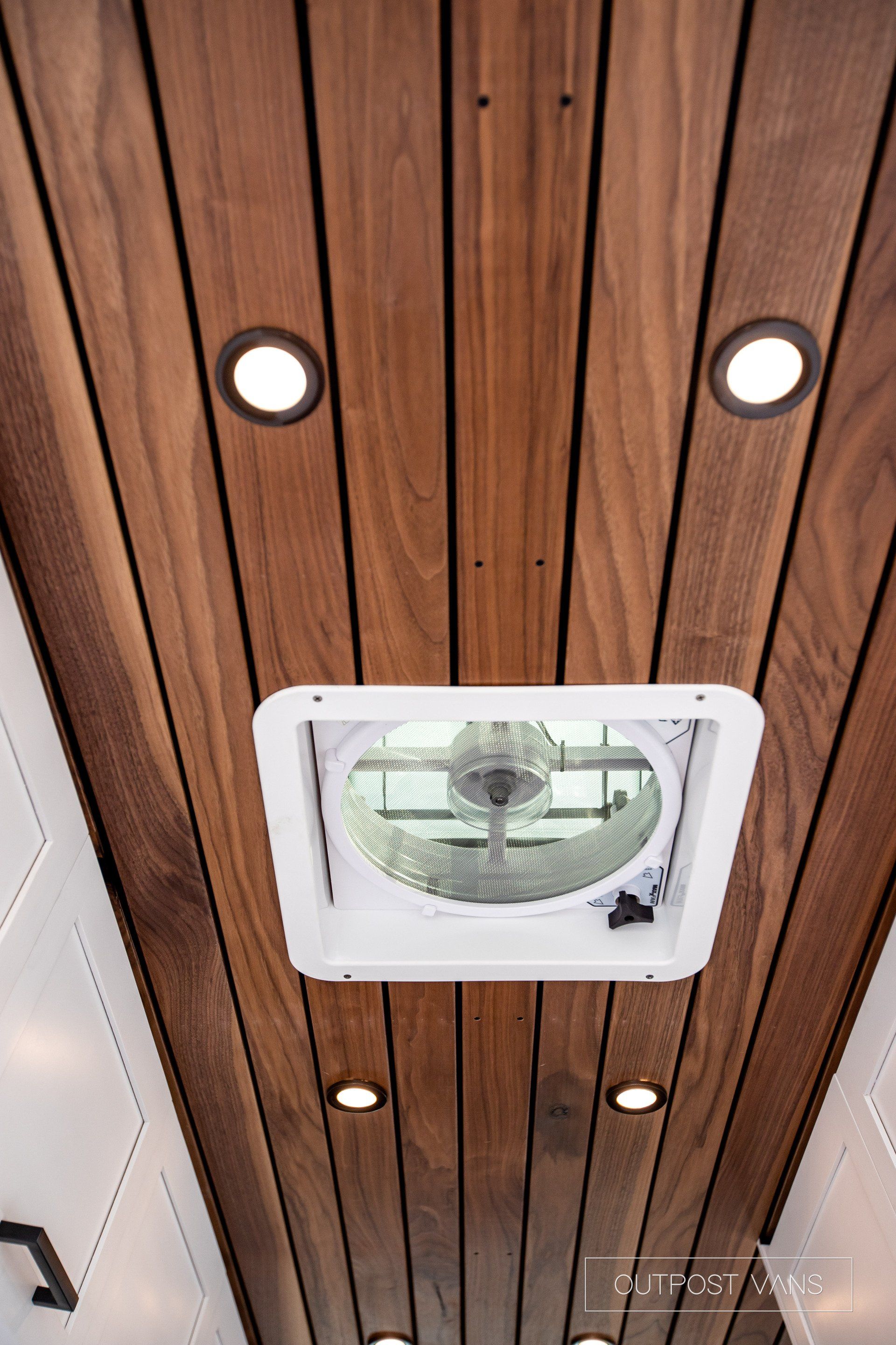 A wooden ceiling with a fan and lights on it.