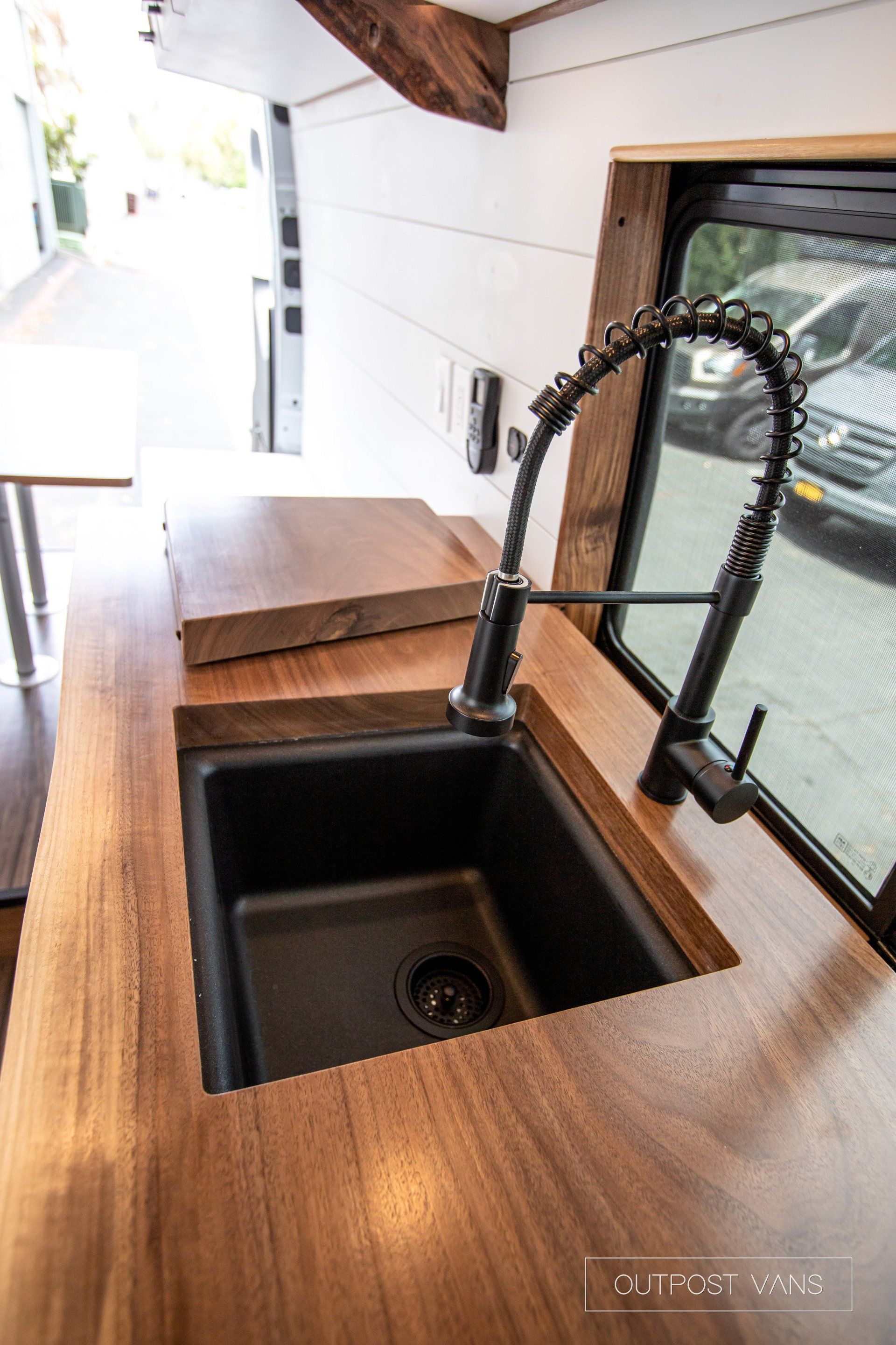 A kitchen sink with a faucet and a wooden counter top.