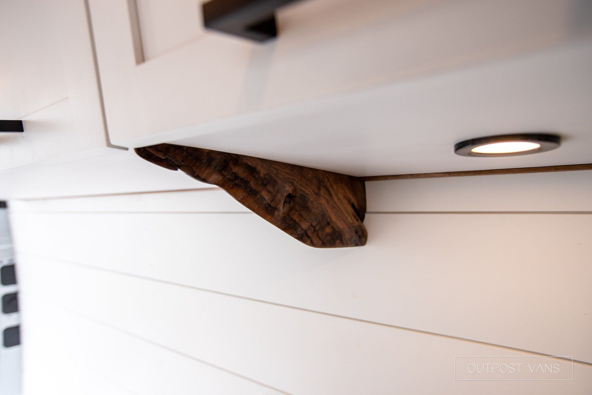 A piece of wood is hanging from the ceiling above a cabinet.