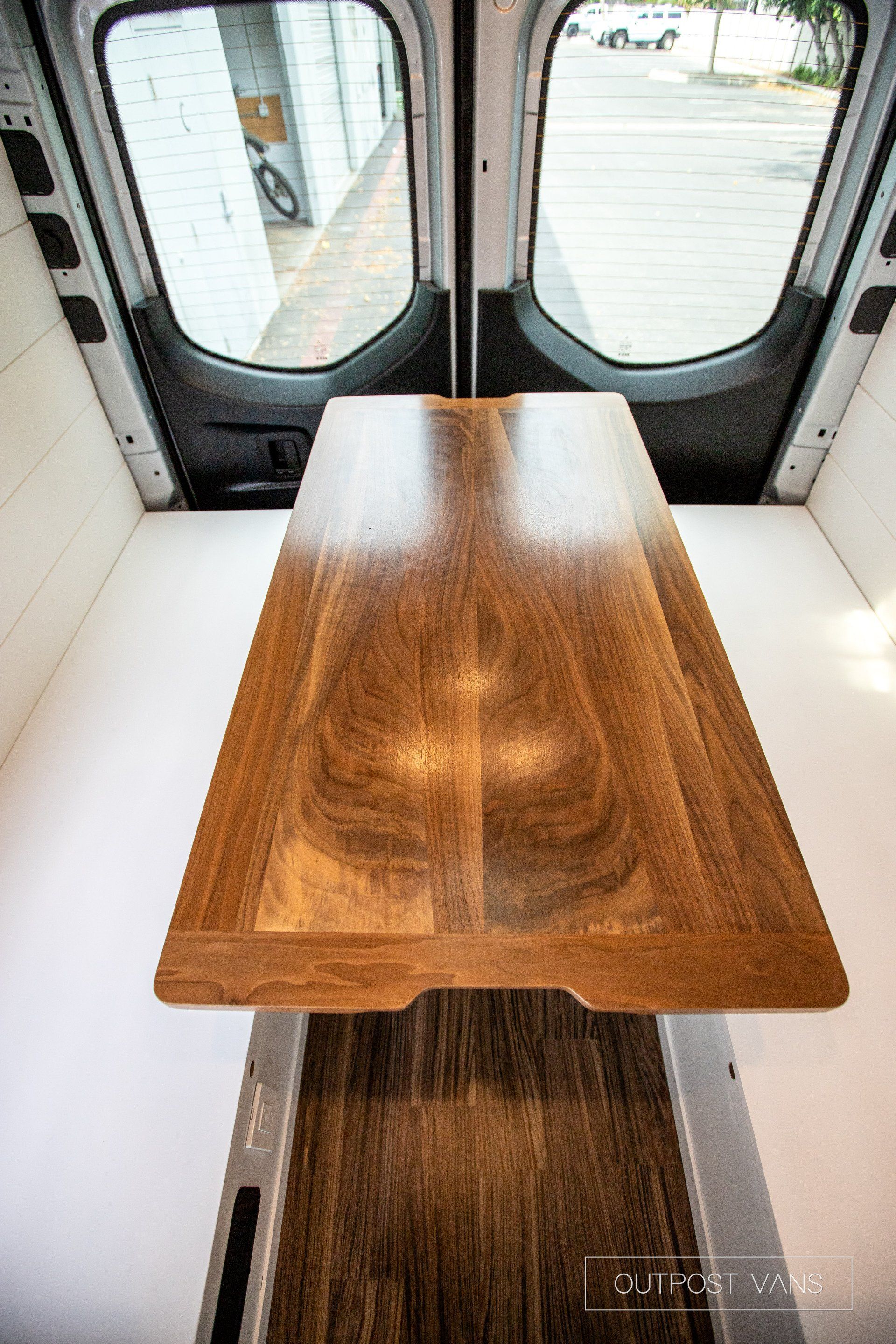 A wooden table is in the back of a van.