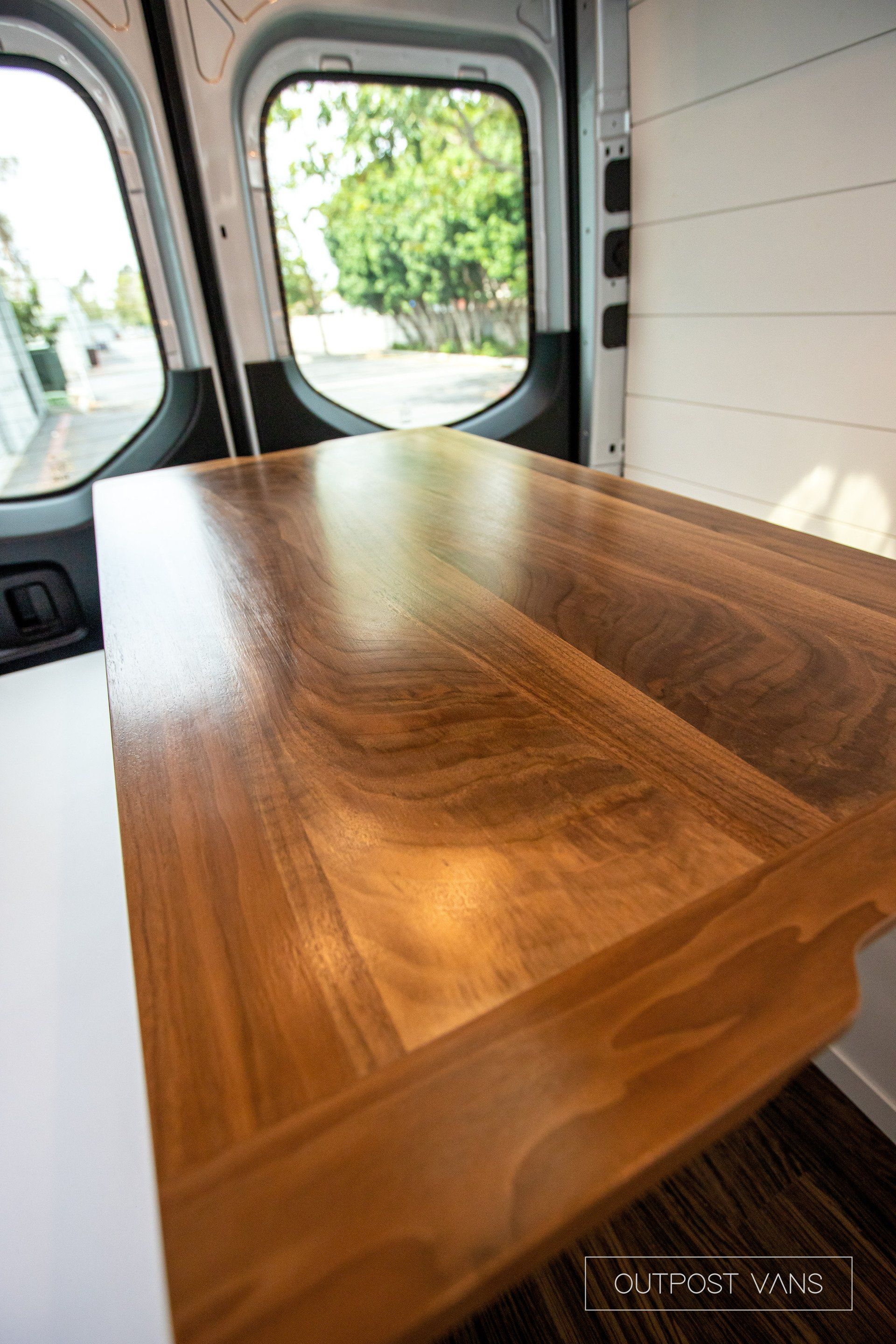 A wooden table is in the back of a van.