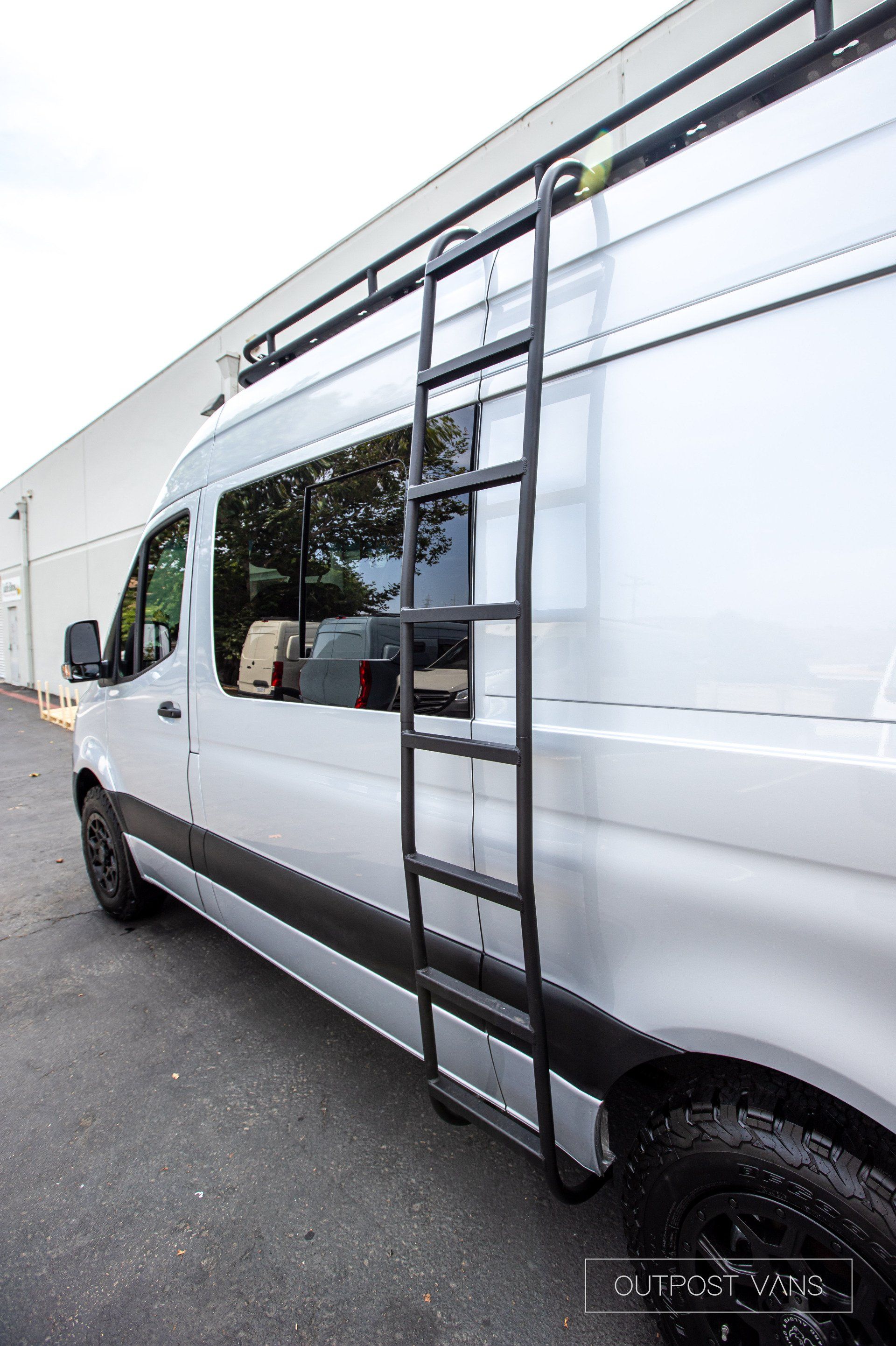A white van with a ladder attached to the side of it.