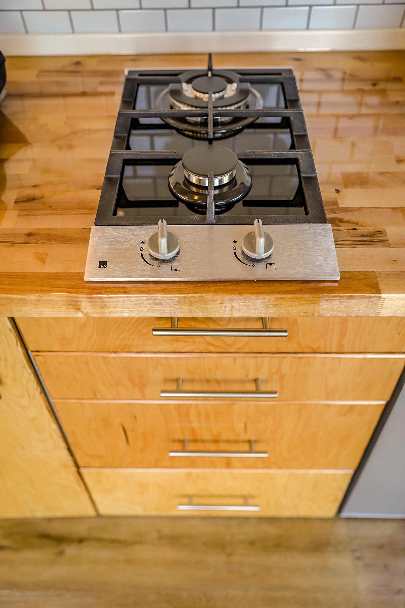 a gas stove is sitting on top of a wooden counter in a kitchen .