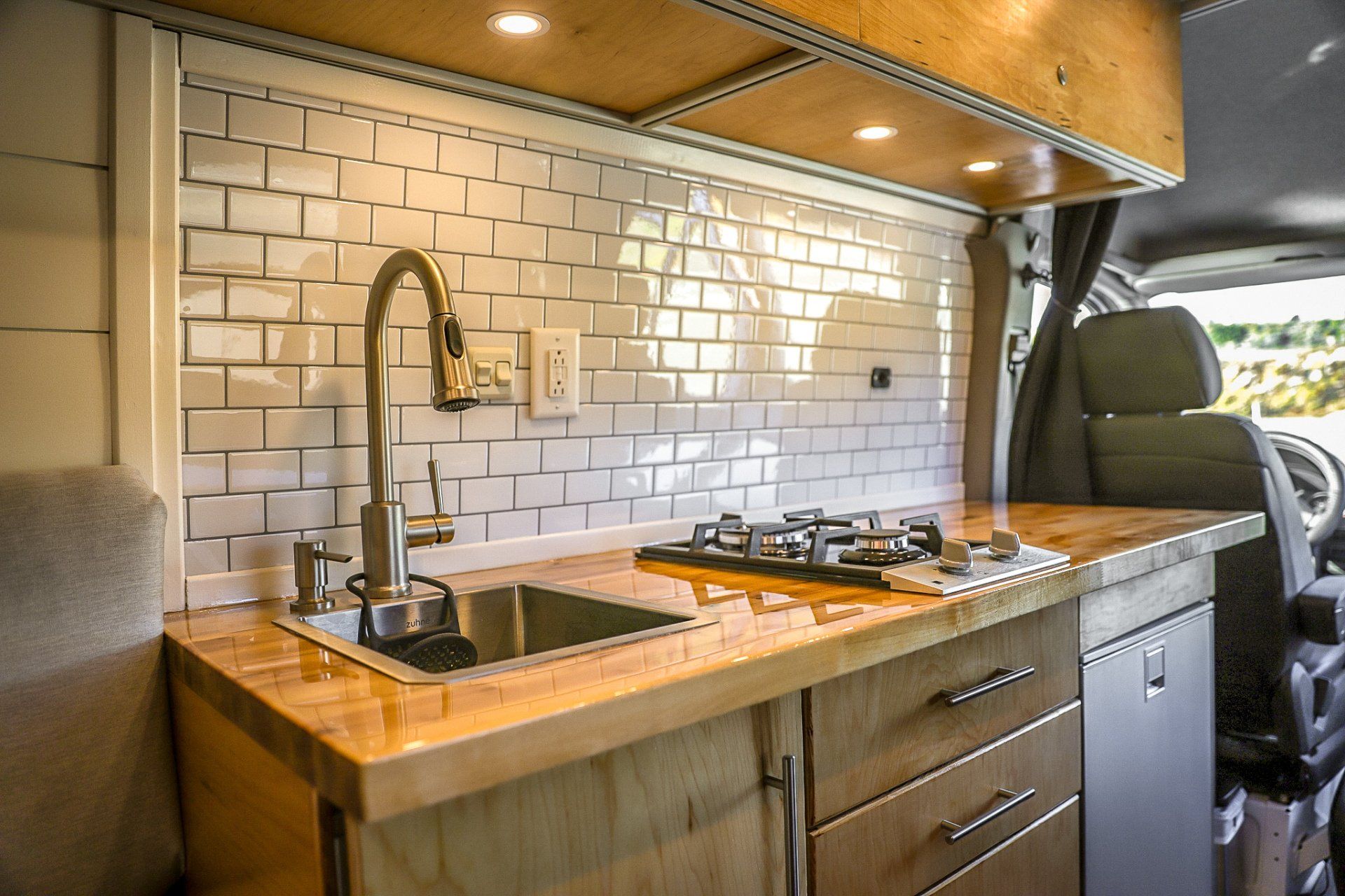a kitchen in a van with a sink , stove , and cabinets .