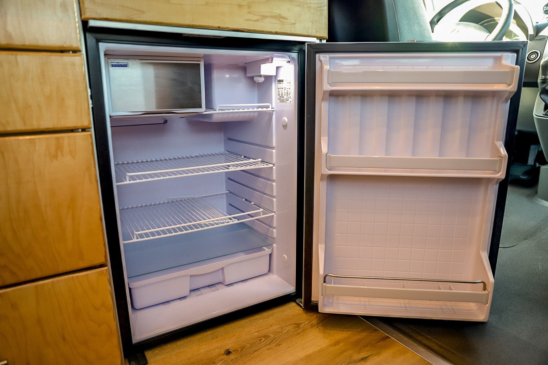 an empty refrigerator with the door open in a kitchen .