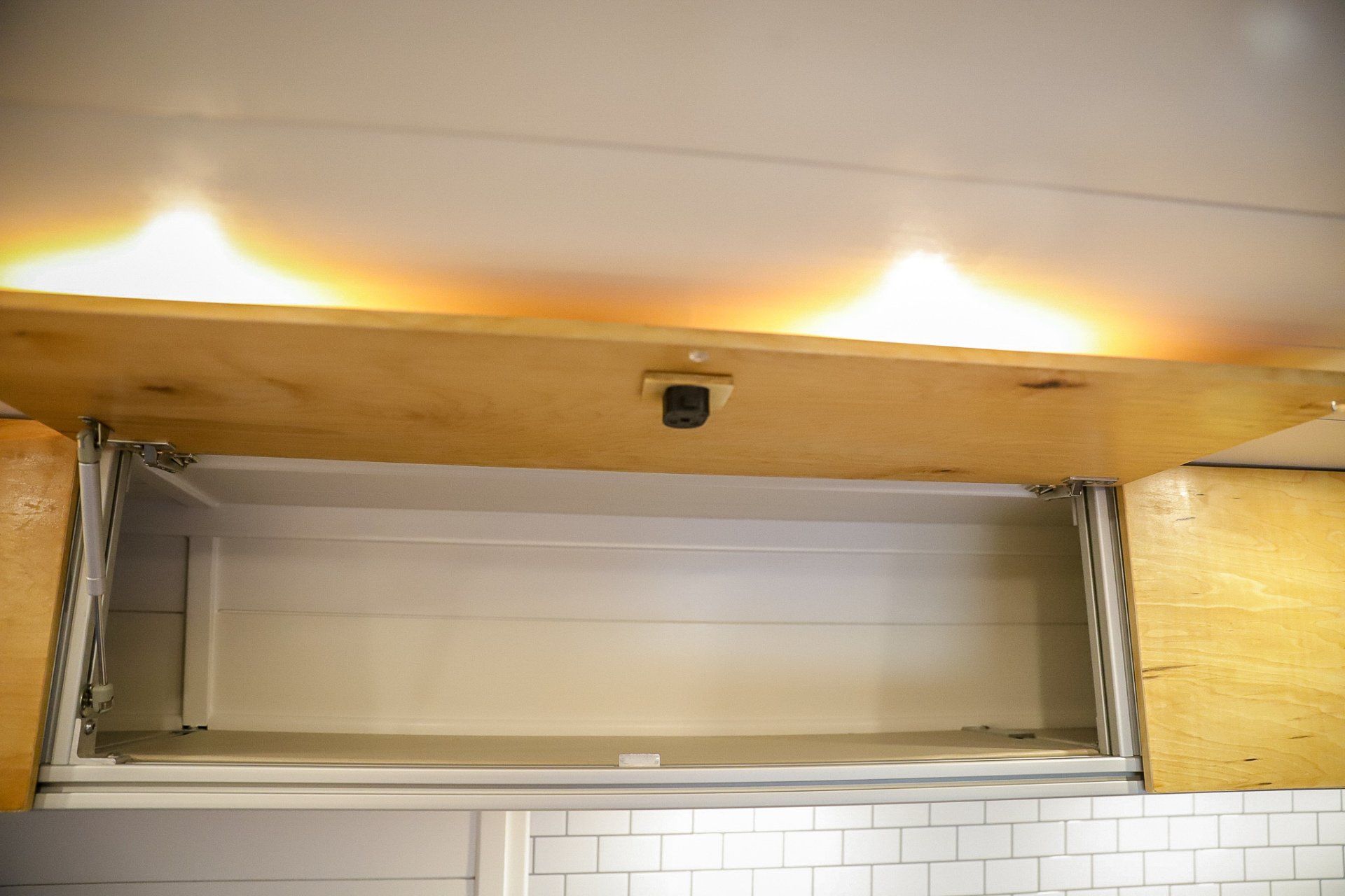 an empty cabinet in a kitchen with the doors open .
