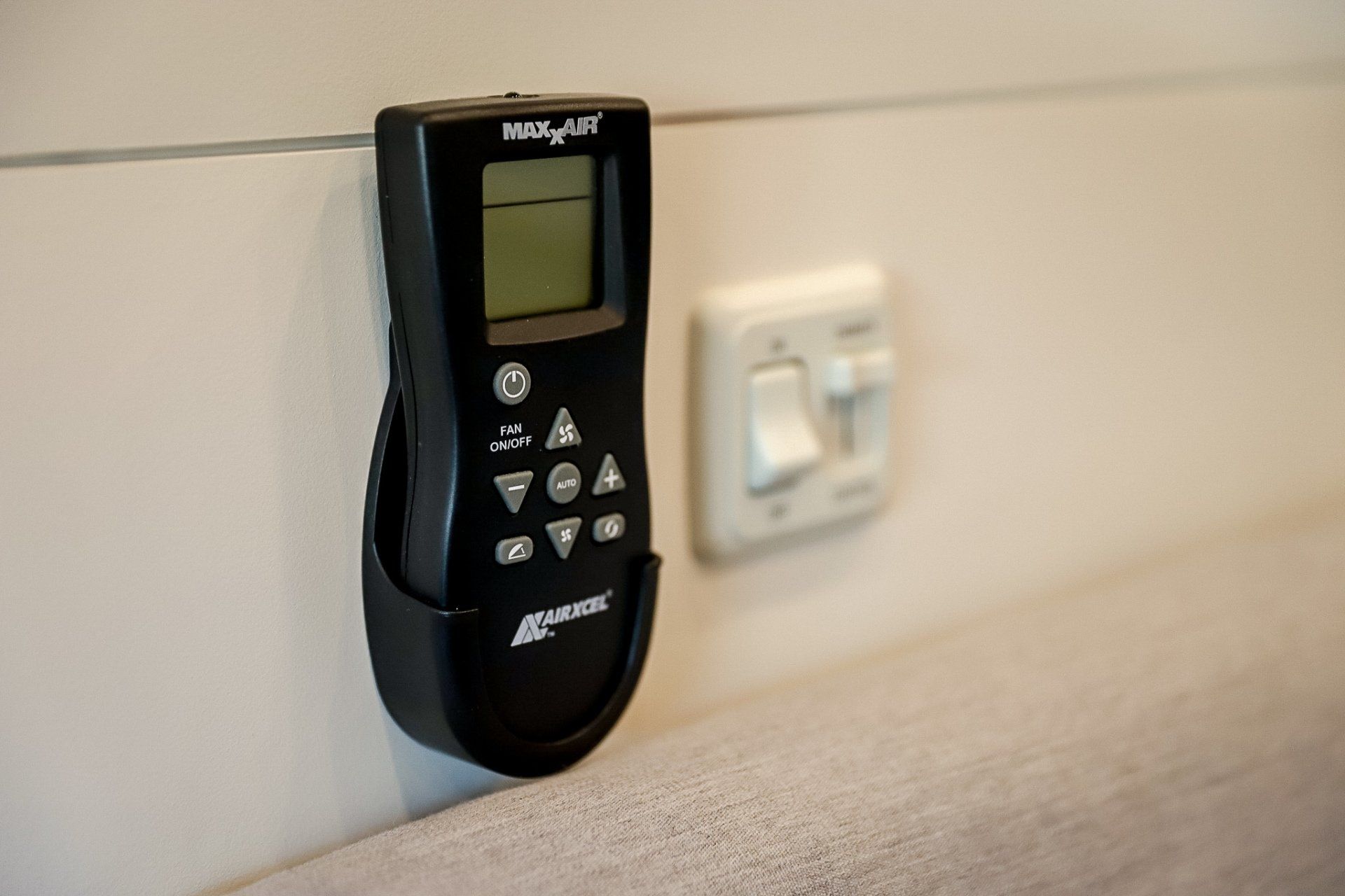 a remote control is hanging on a wall next to a switch .