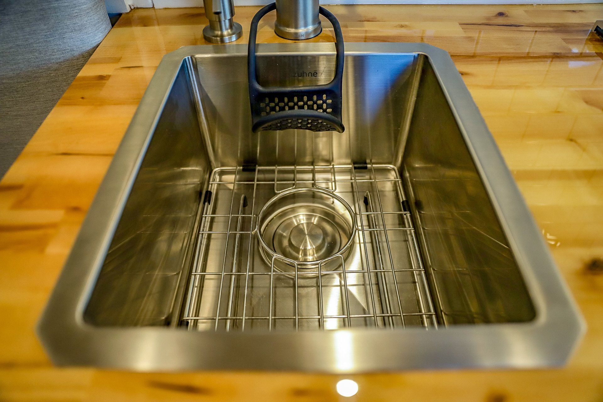 a stainless steel kitchen sink is sitting on top of a wooden counter .