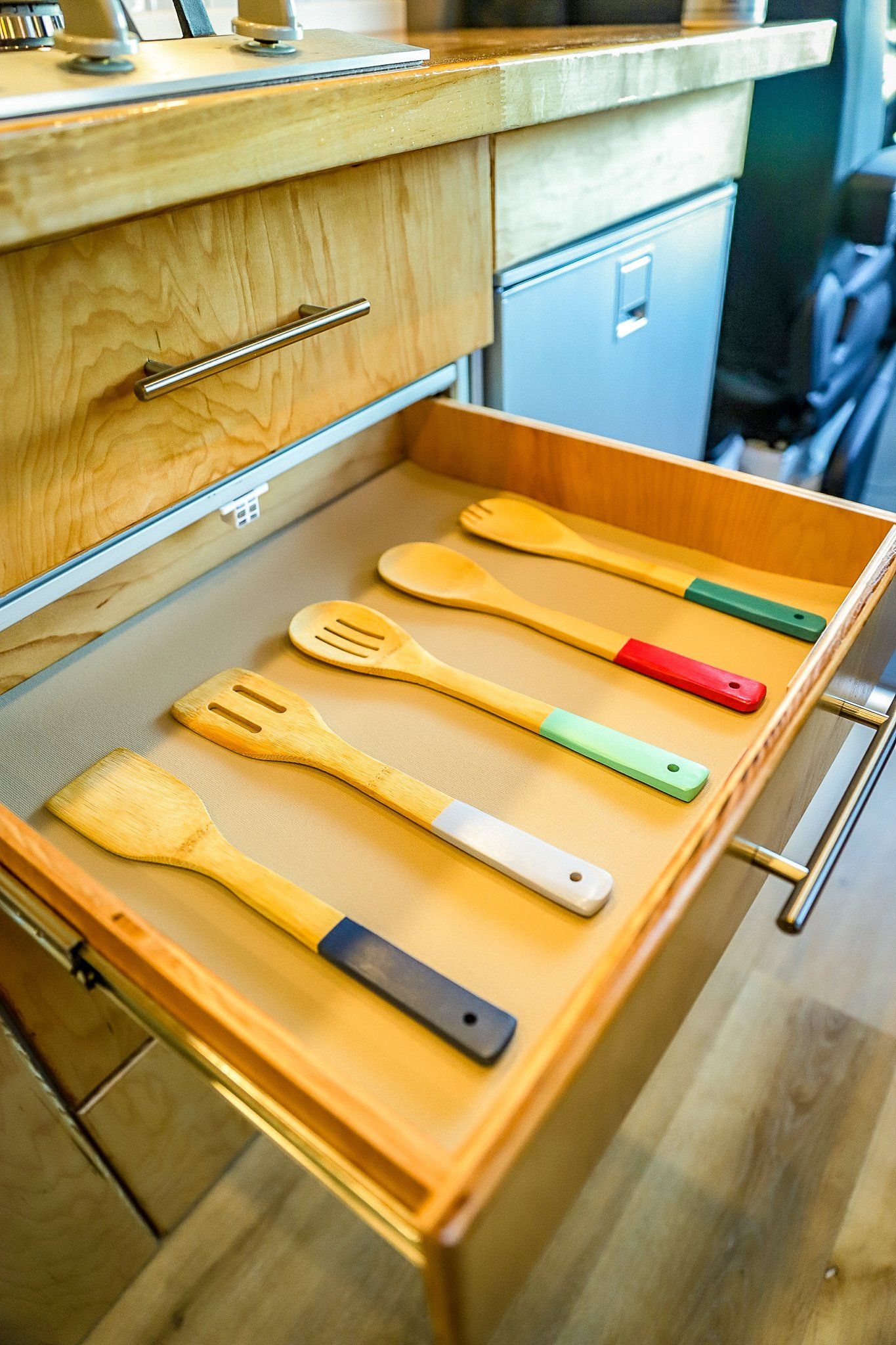 a wooden drawer filled with wooden utensils in a kitchen .