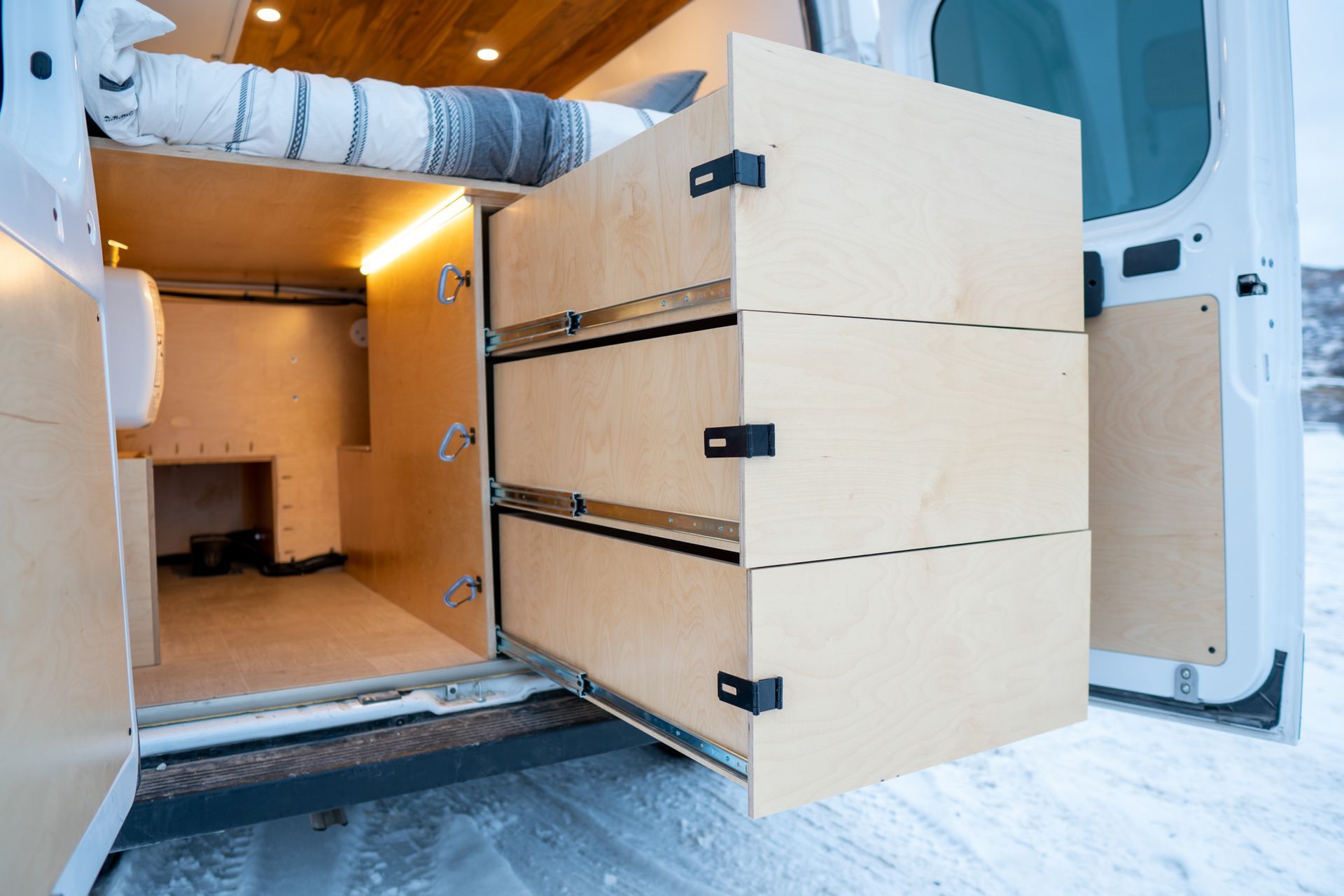 A van with a bed and drawers in the back of it.