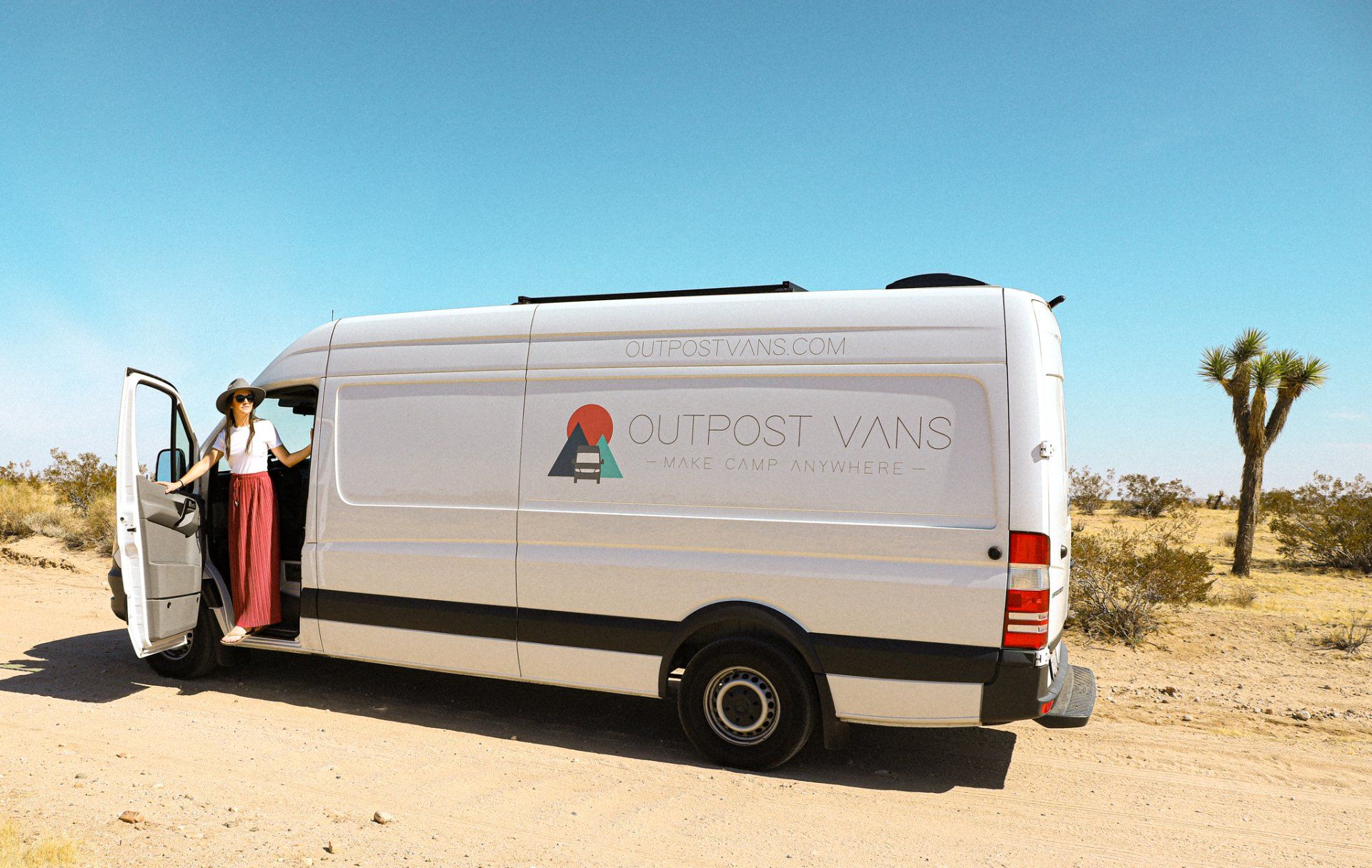 a woman is getting out of a white van in the desert .