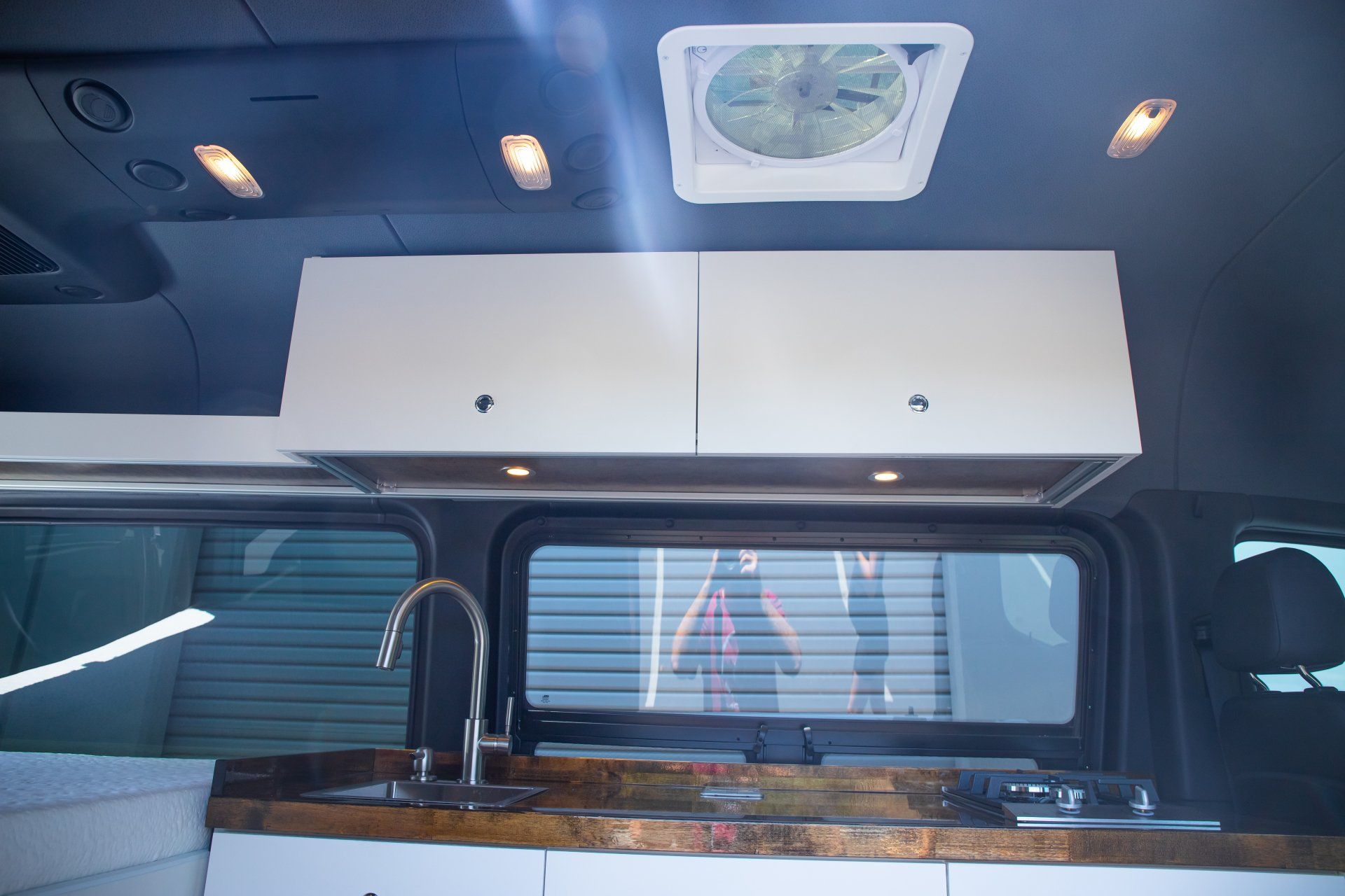 a kitchen in a van with a sink and a fan on the ceiling .