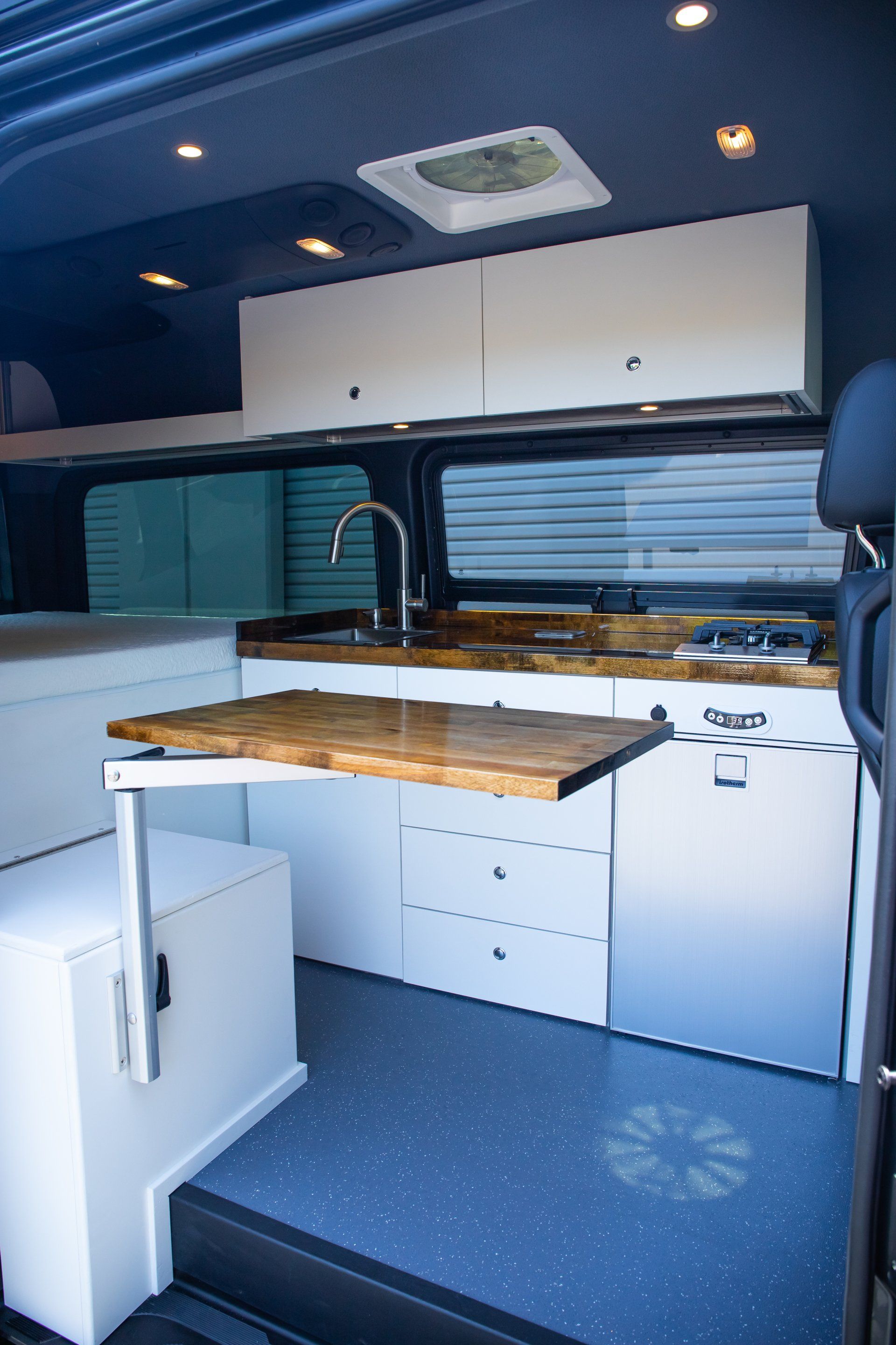 a kitchen in a van with a table that can be pulled out .