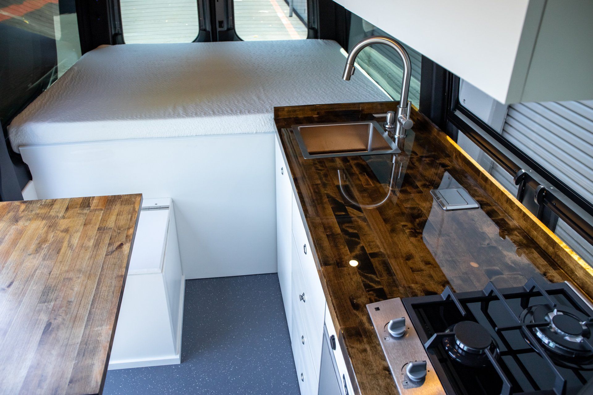 a kitchen in a van with a sink , stove , and table .