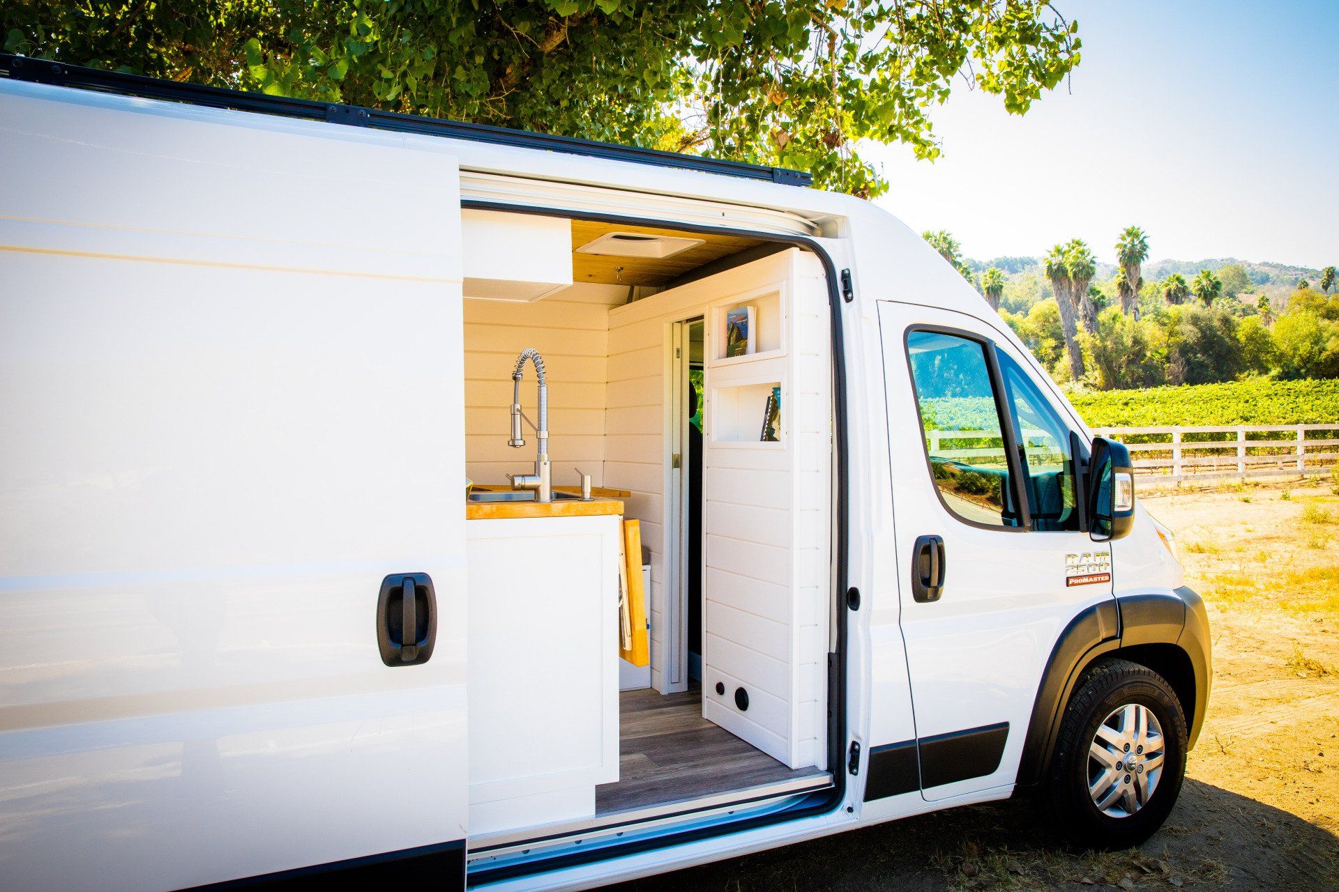 a white van with the door open is parked in a field .