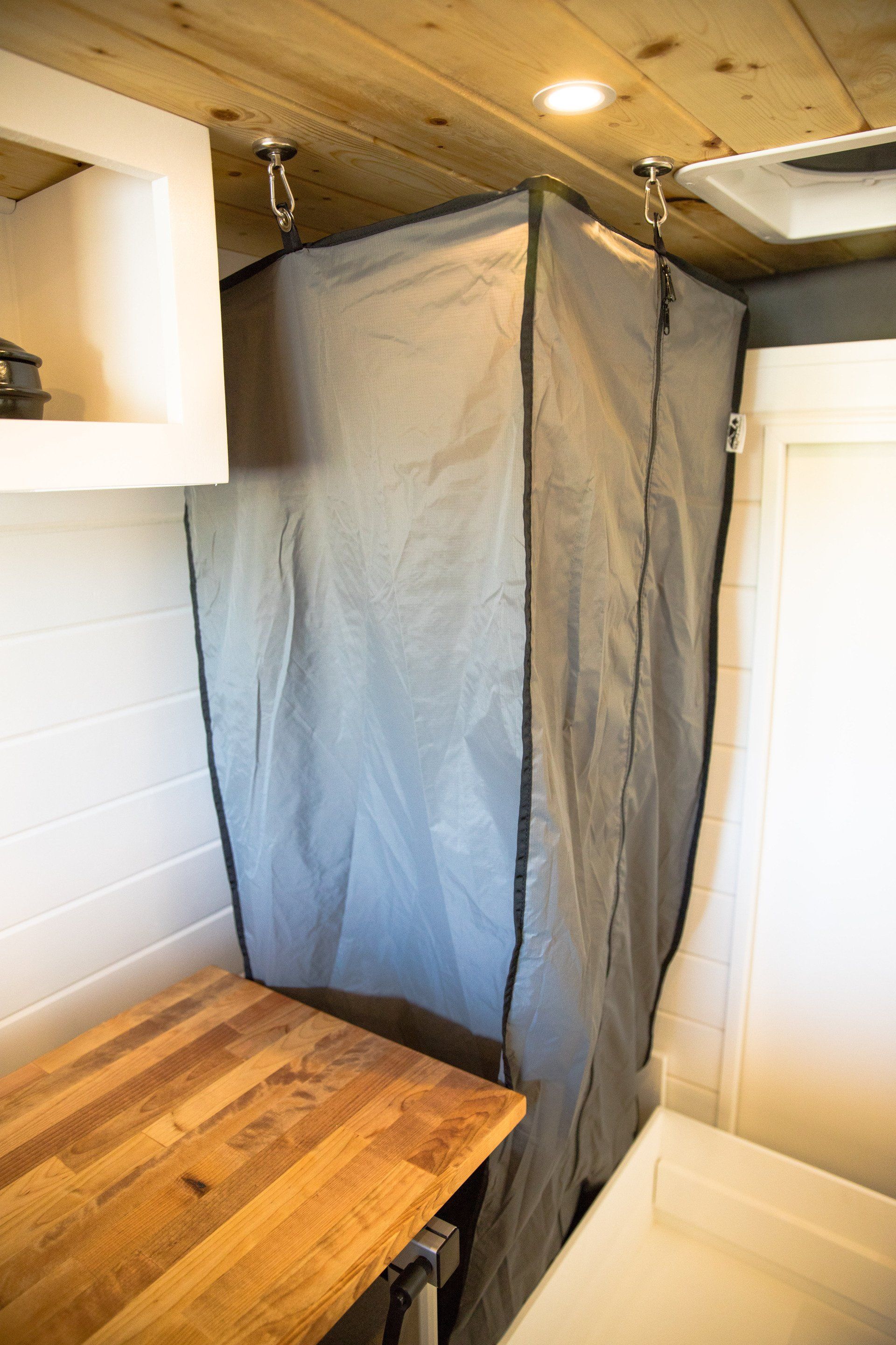 a shower curtain is hanging from the ceiling in a bathroom next to a wooden table .