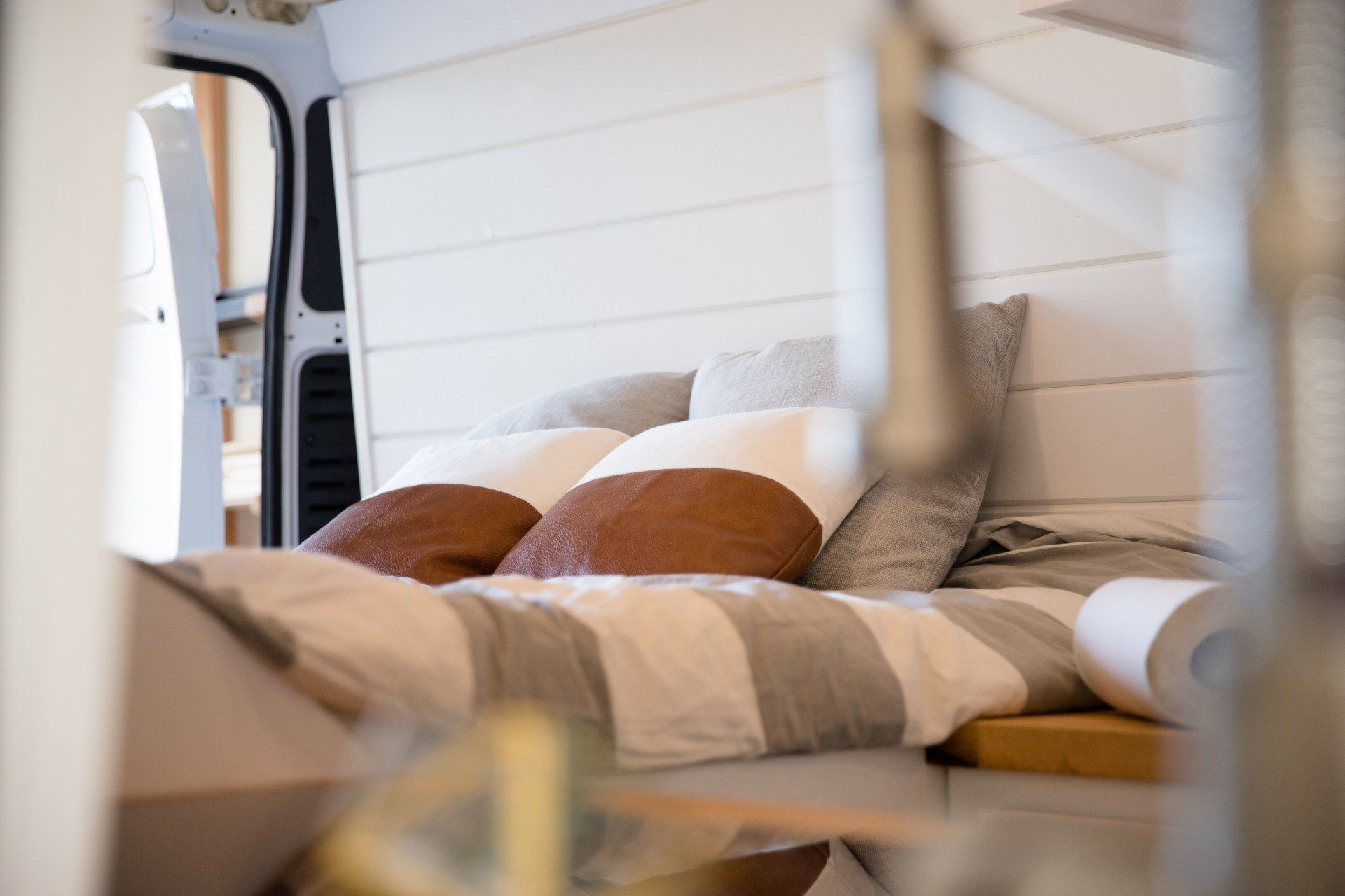 a bed with striped sheets and pillows in the back of a van .
