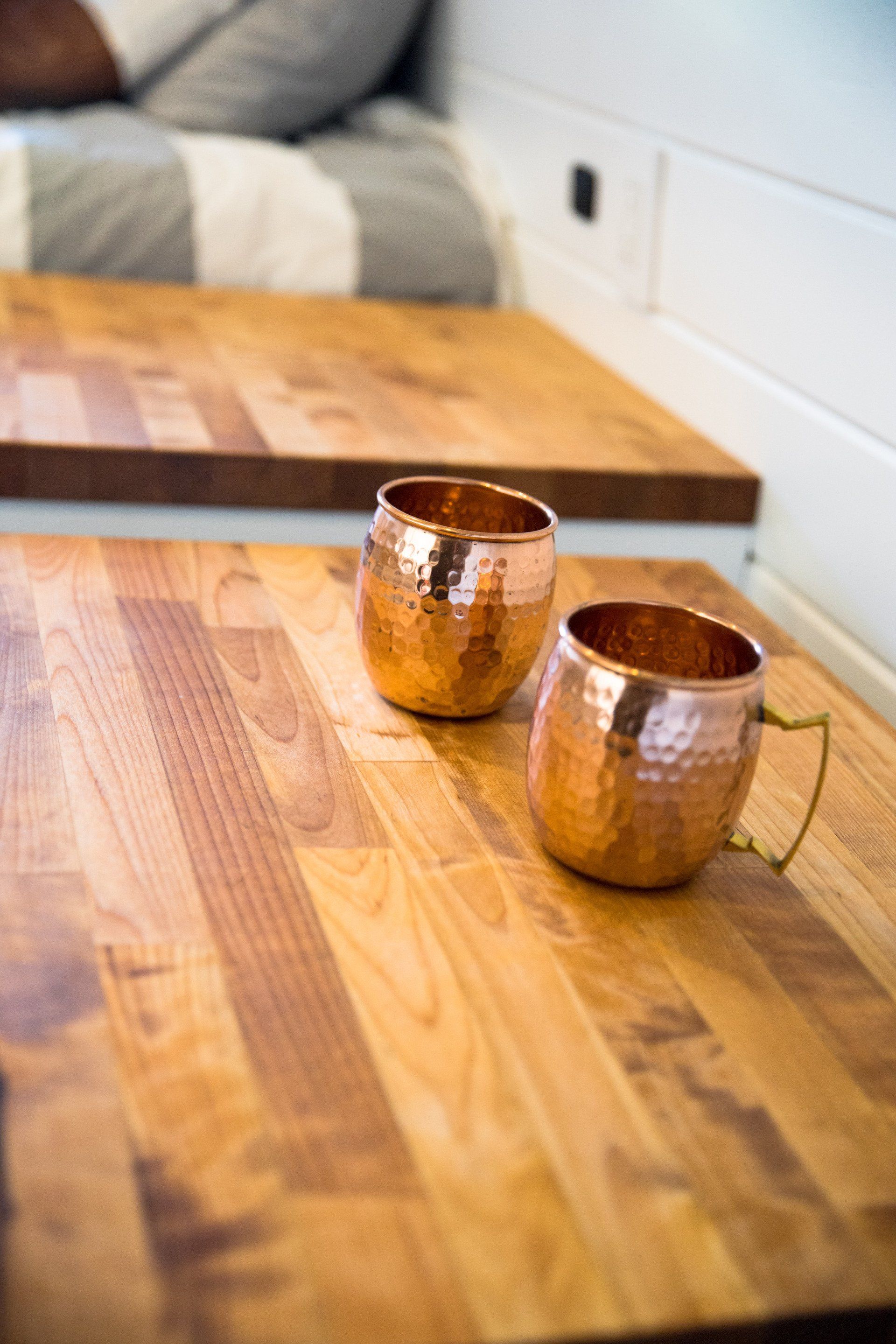 two copper mugs are sitting on a wooden table .