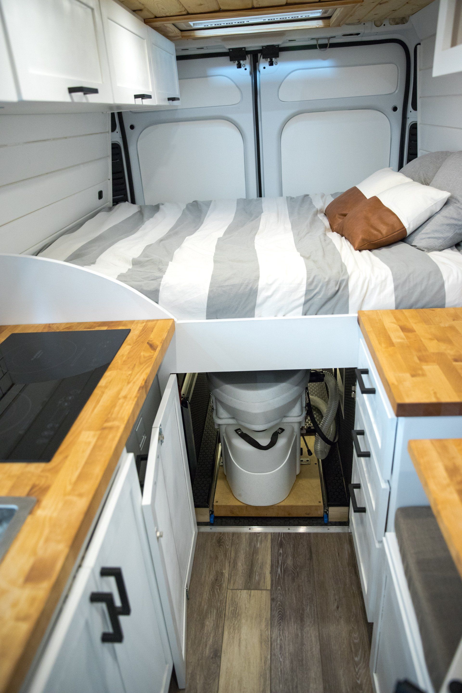 a camper van with a bed and a toilet underneath it .