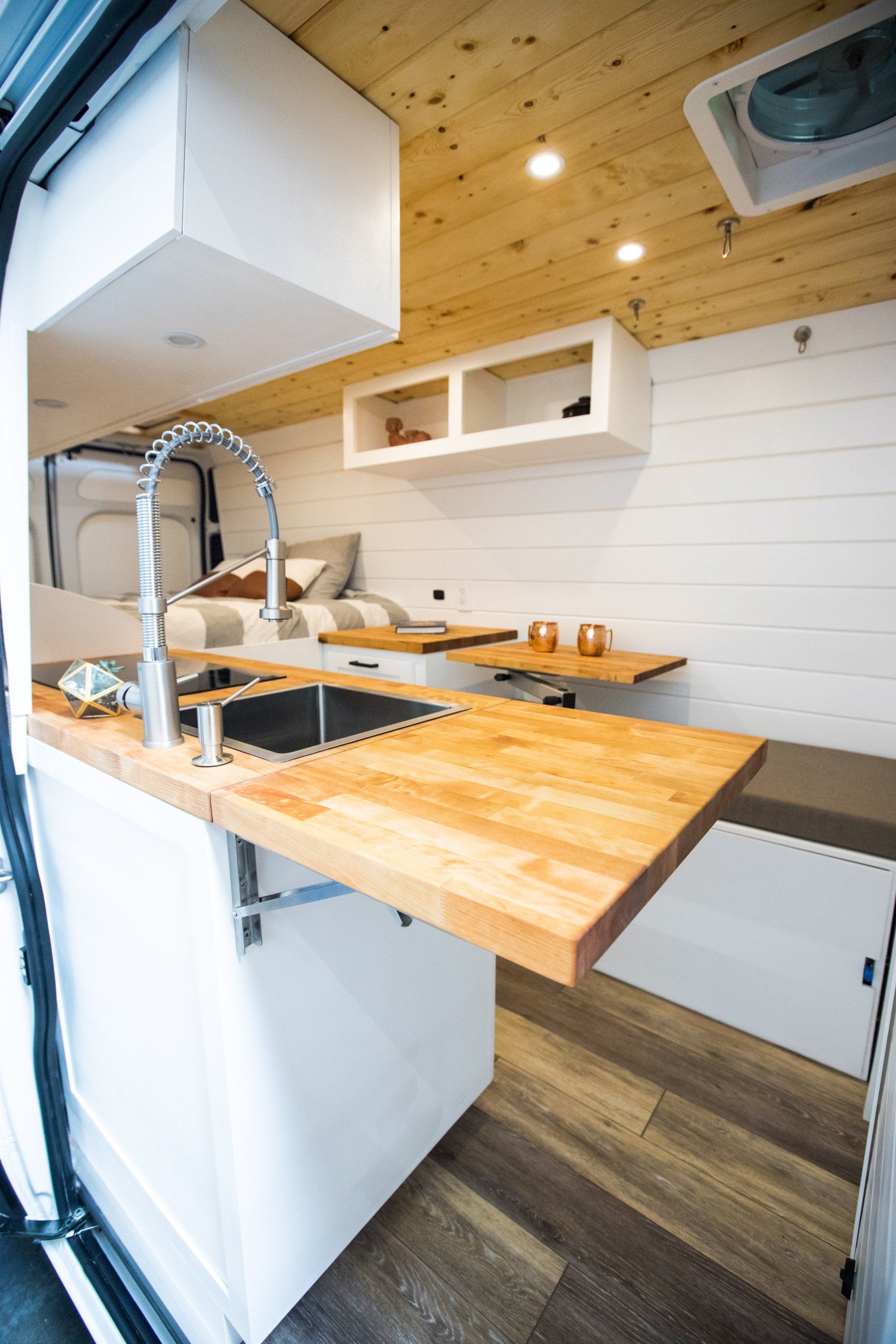 a kitchen in a van with a sink and wooden counter tops .