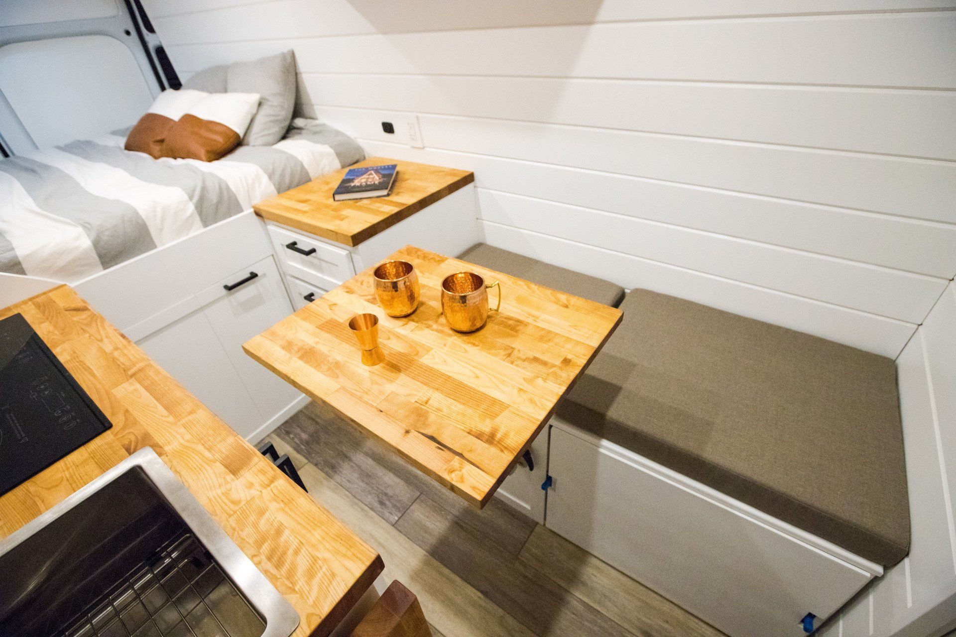 a wooden table is sitting on a bench in a room next to a bed .