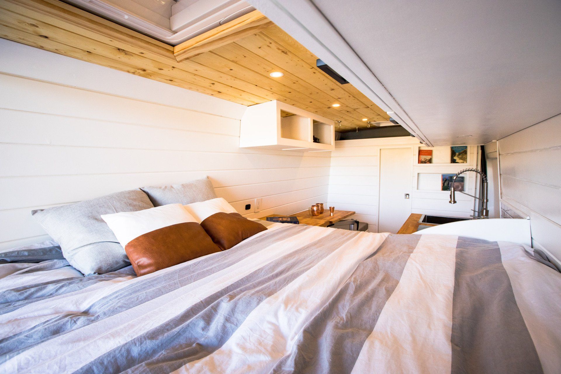 a bed with a striped blanket and pillows in a small room .