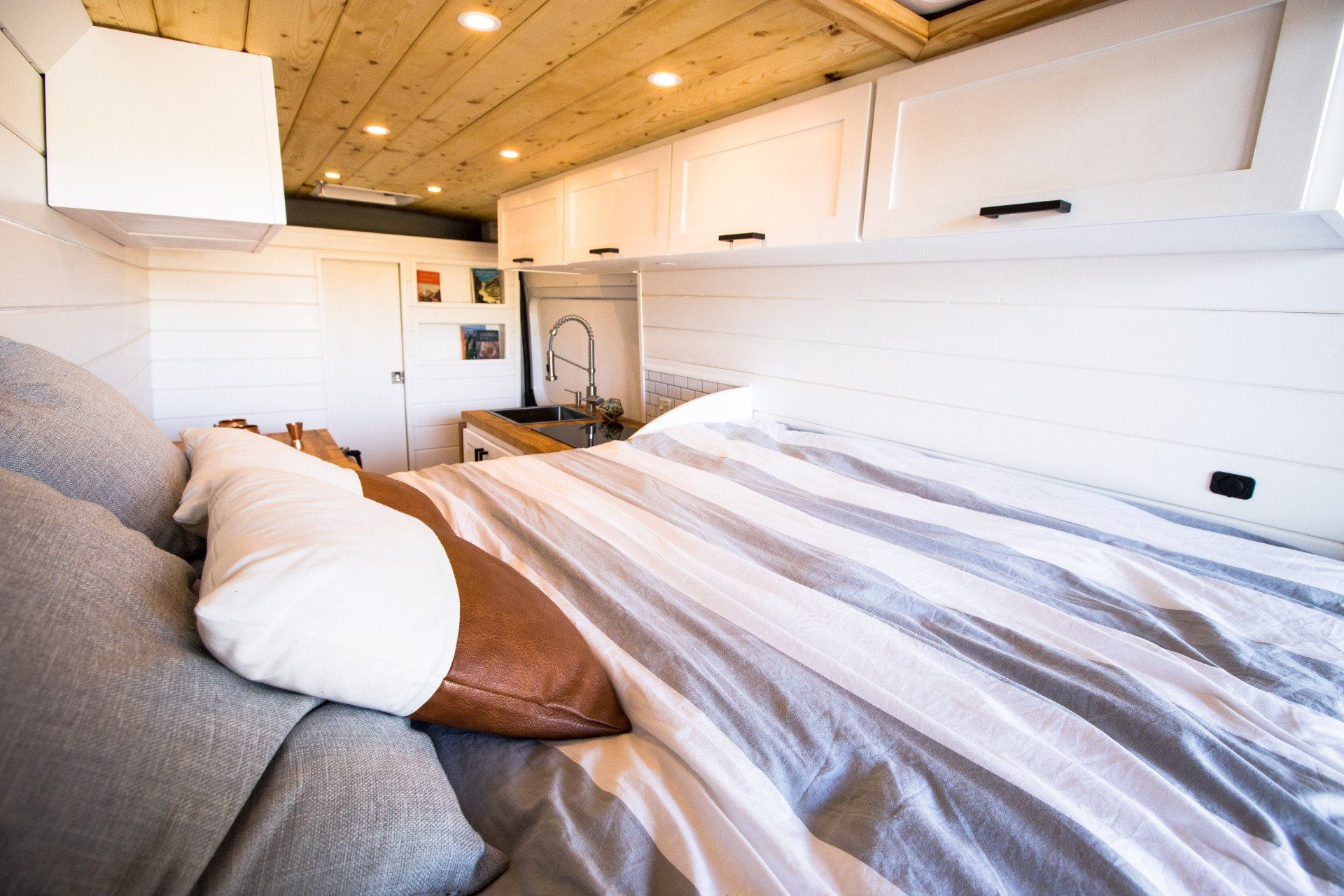 a bed with a striped blanket and pillows in a camper van .