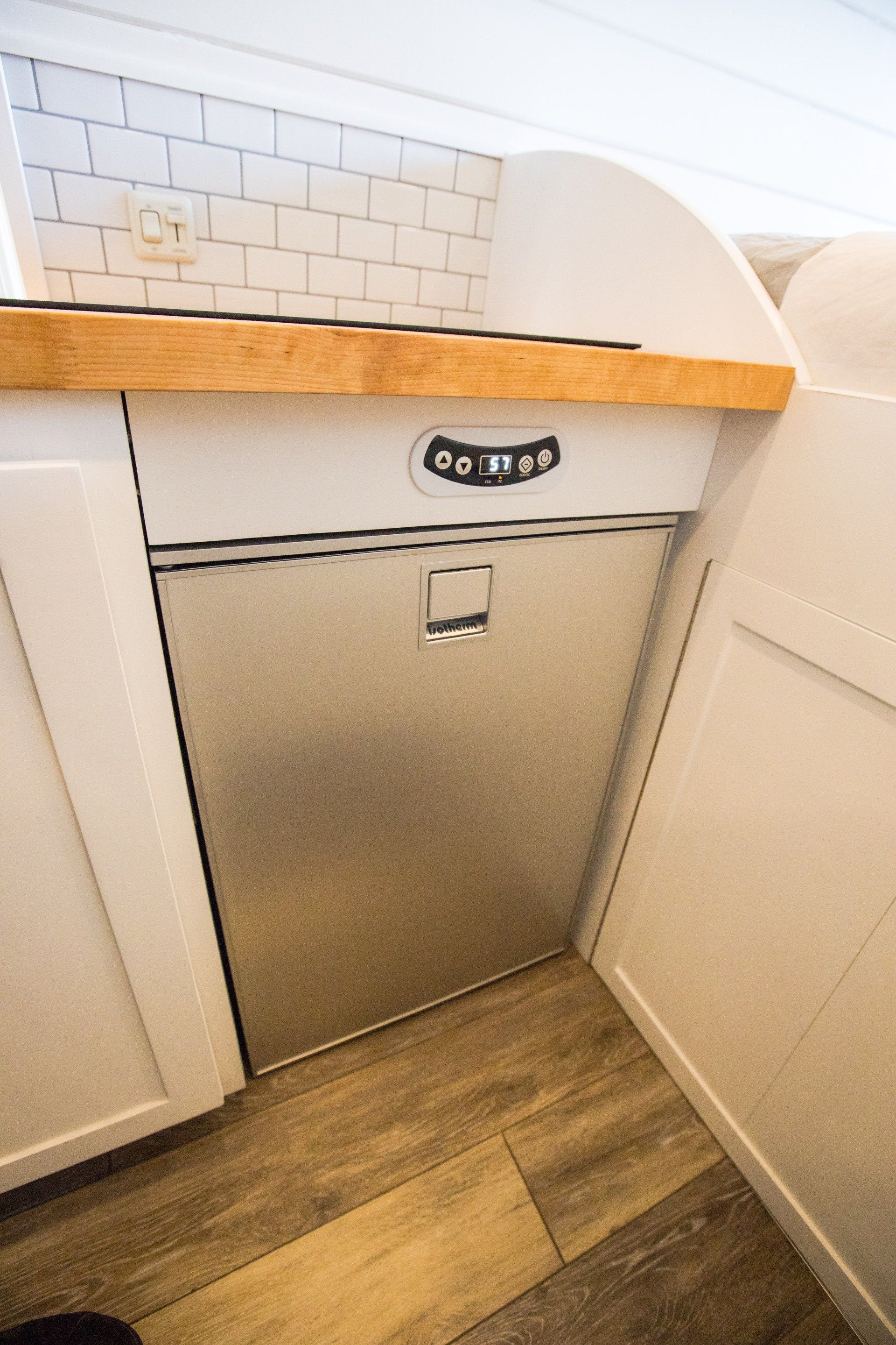 a stainless steel refrigerator is sitting under a wooden counter in a kitchen .