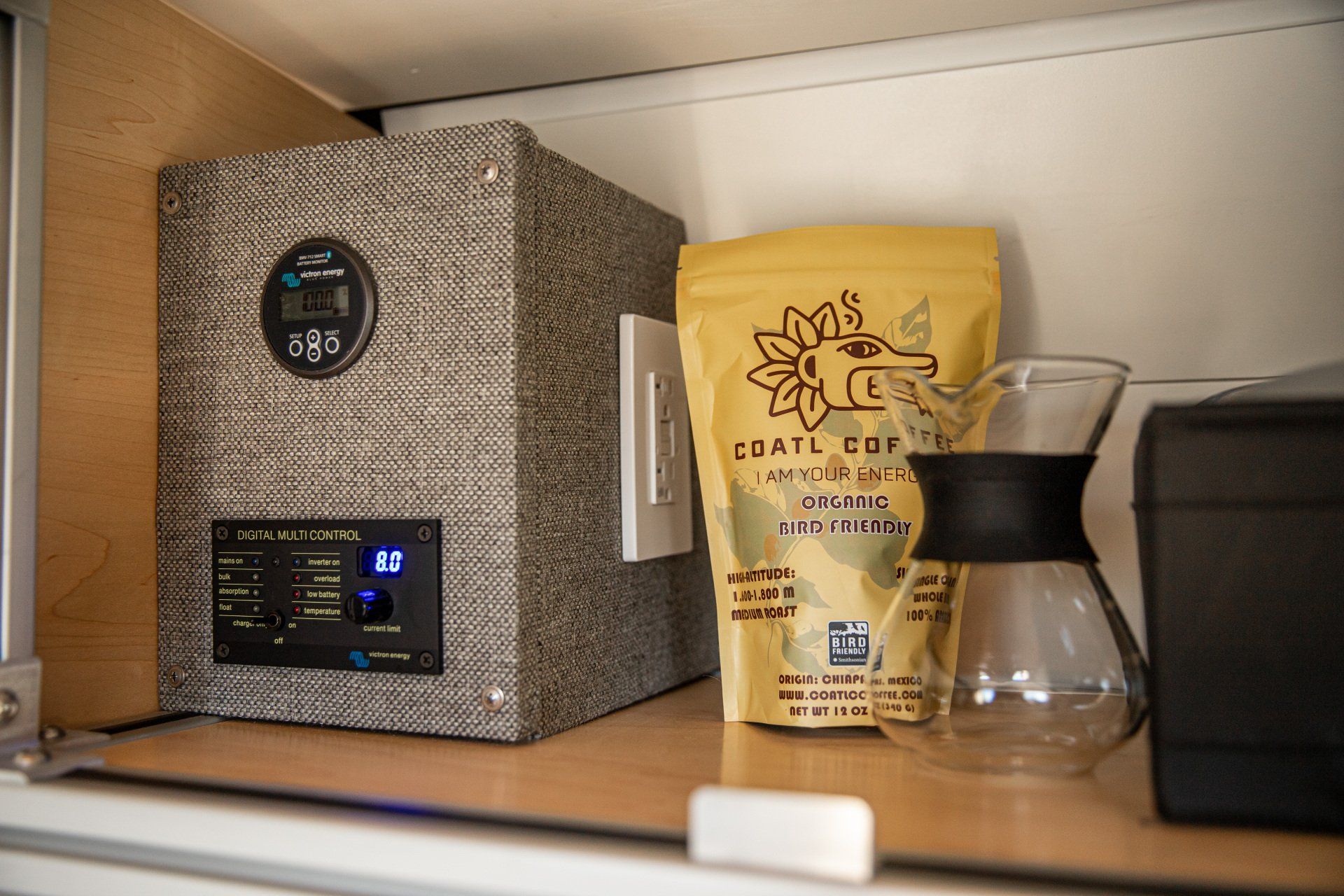 a bag of coffee is sitting on a shelf next to a coffee maker .