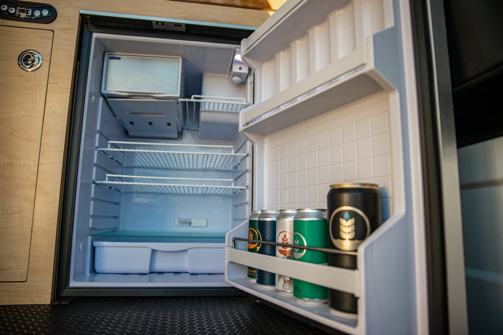 a refrigerator with the door open and cans of beer on the shelves .
