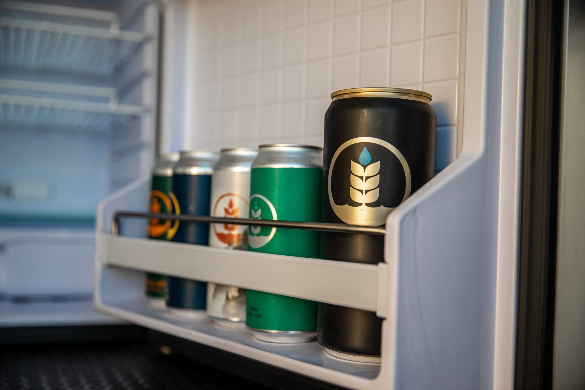 a fridge with a shelf full of cans of soda .