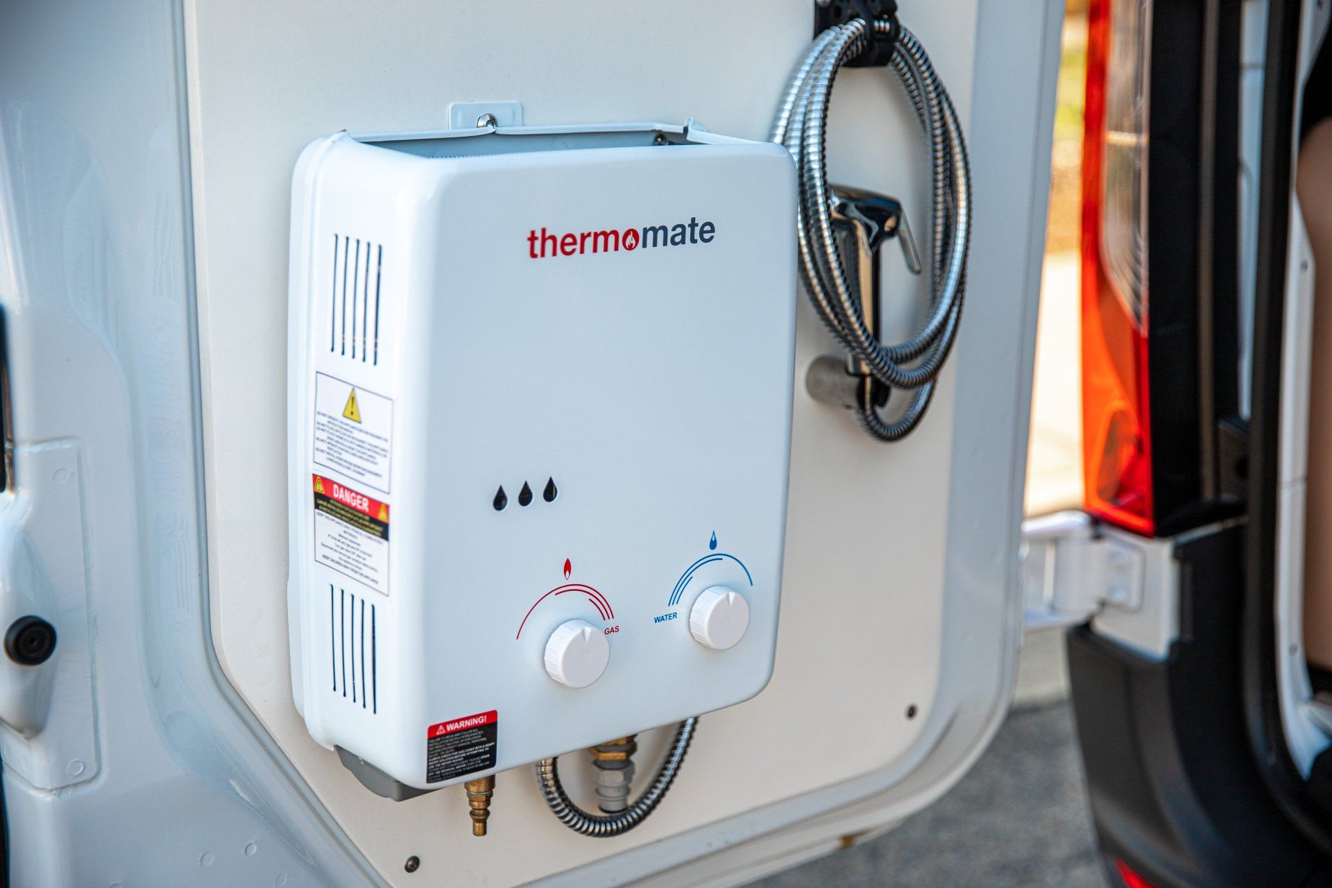 a white water heater is attached to the back of a van .