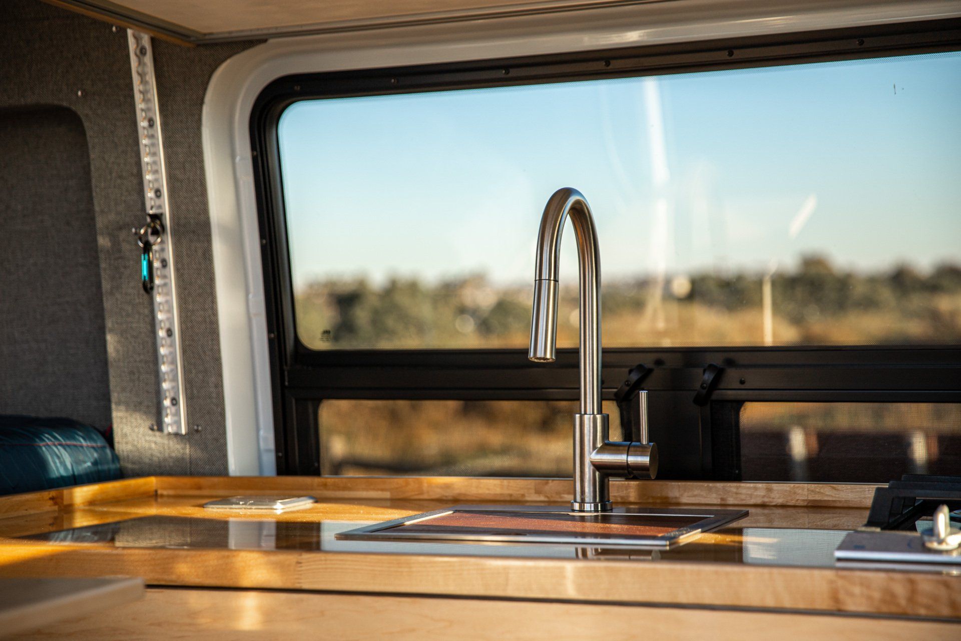 a kitchen sink in a van with a window in the background .