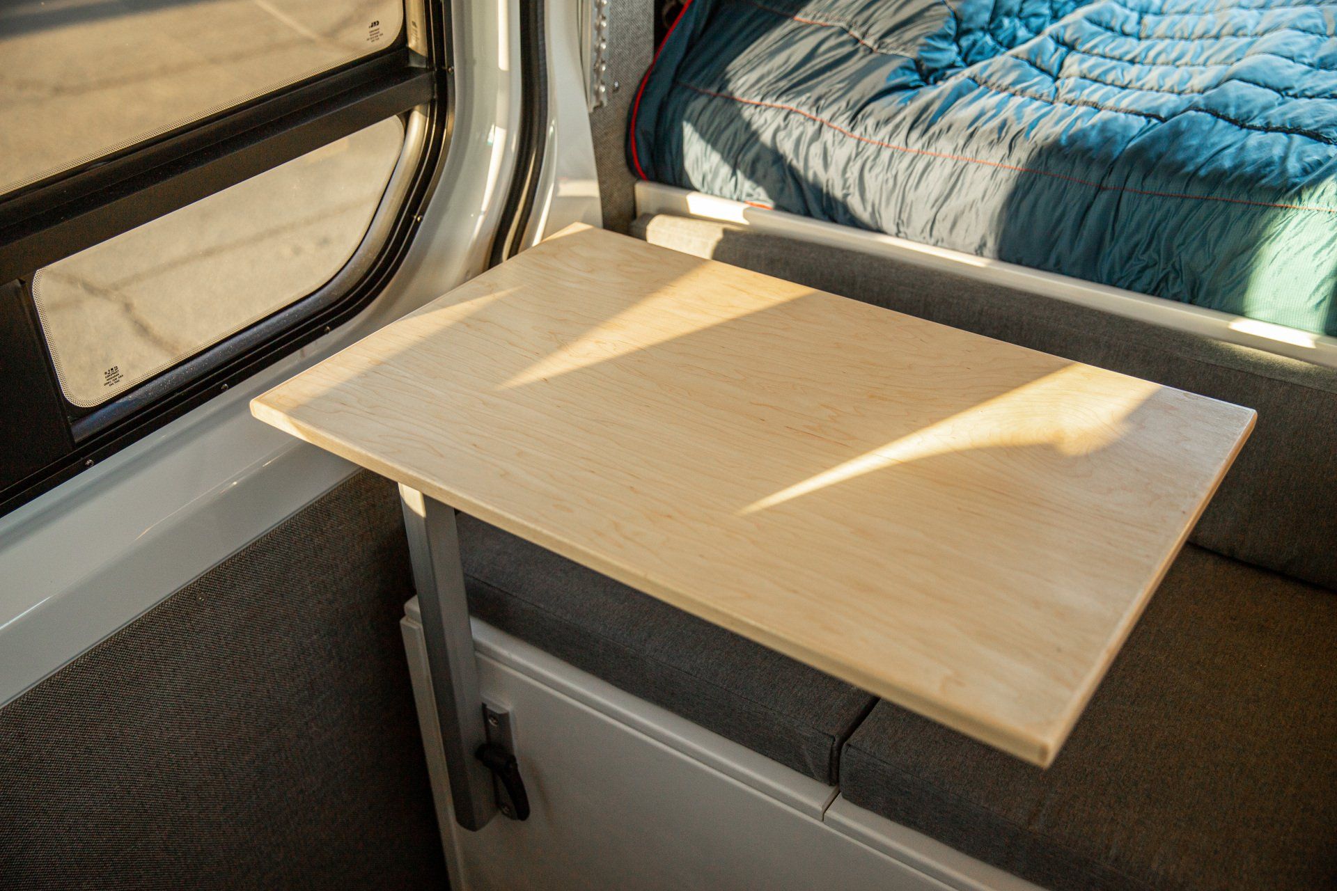 a wooden table is sitting in the back of a van next to a bed .