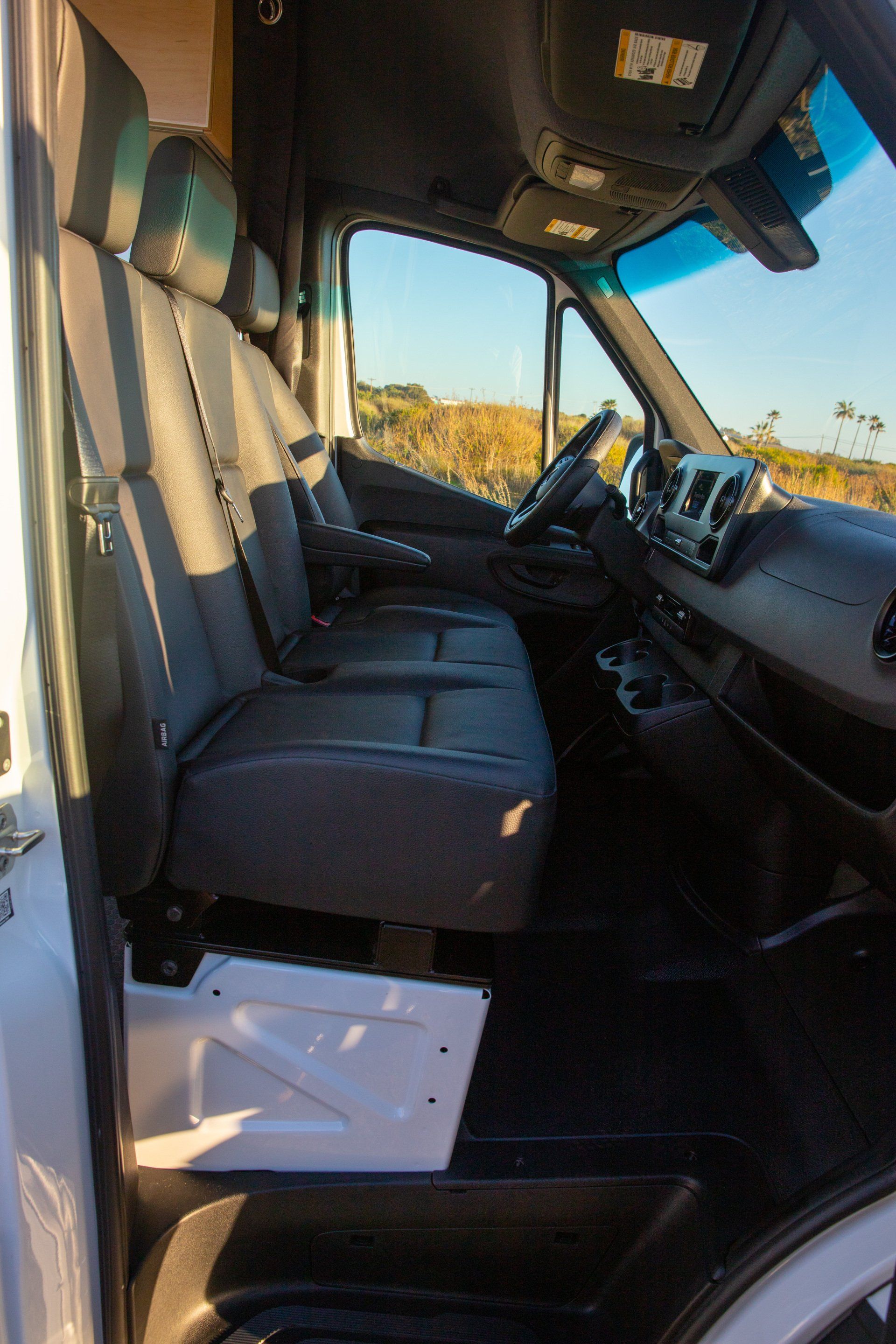 the inside of a white van with black seats and a steering wheel .