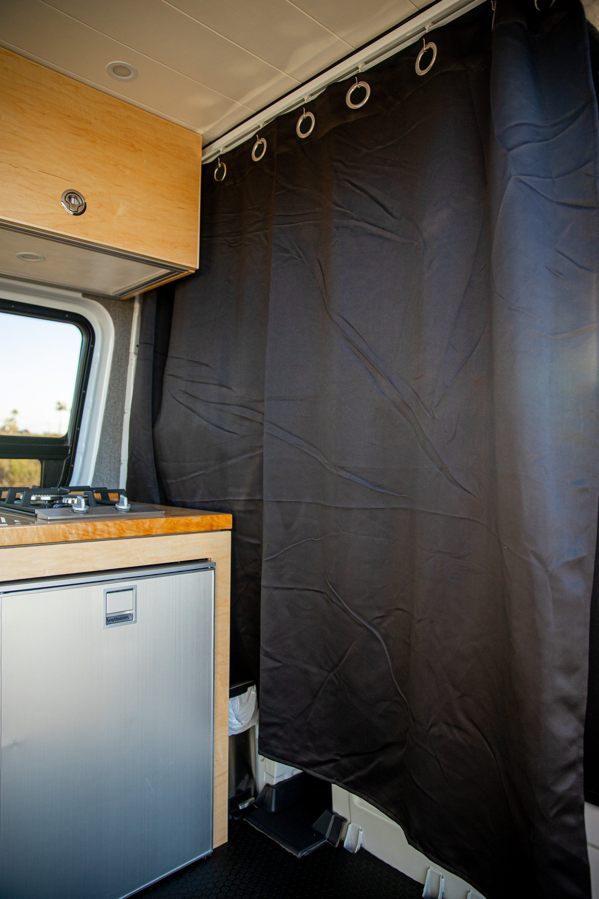 a kitchen in a van with a black curtain hanging on the wall .